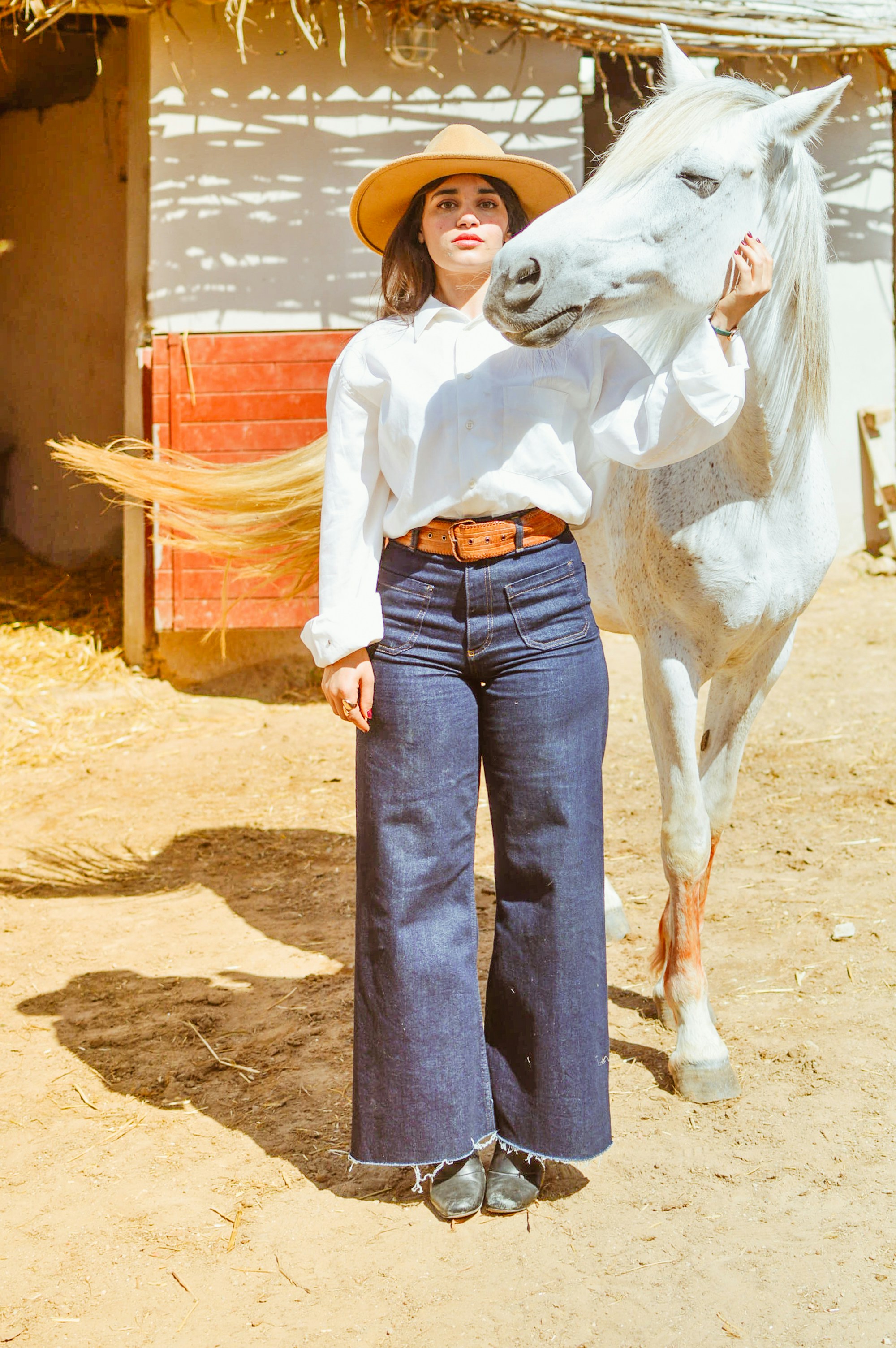 A woman and a white horse pose together.