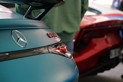 A teal mercedes-benz gt is shown with a red car.