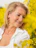 A woman smiles among yellow flowers.