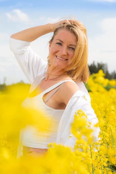 Woman smiles in a field of yellow flowers.