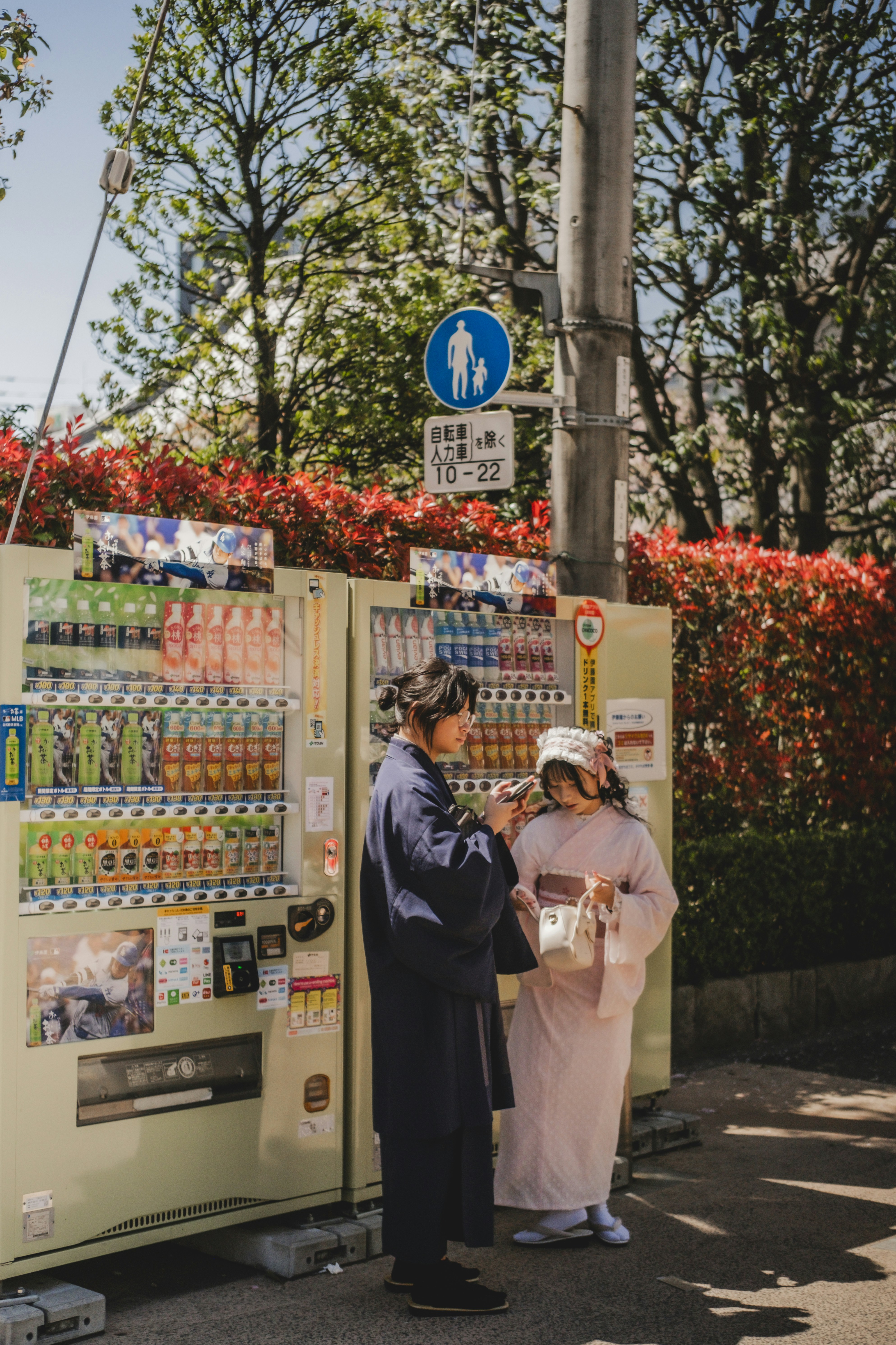 음료 자판기 옆에는 두 사람이 서 있습니다.