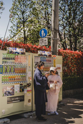 Two people are standing next to a drink vending machine.