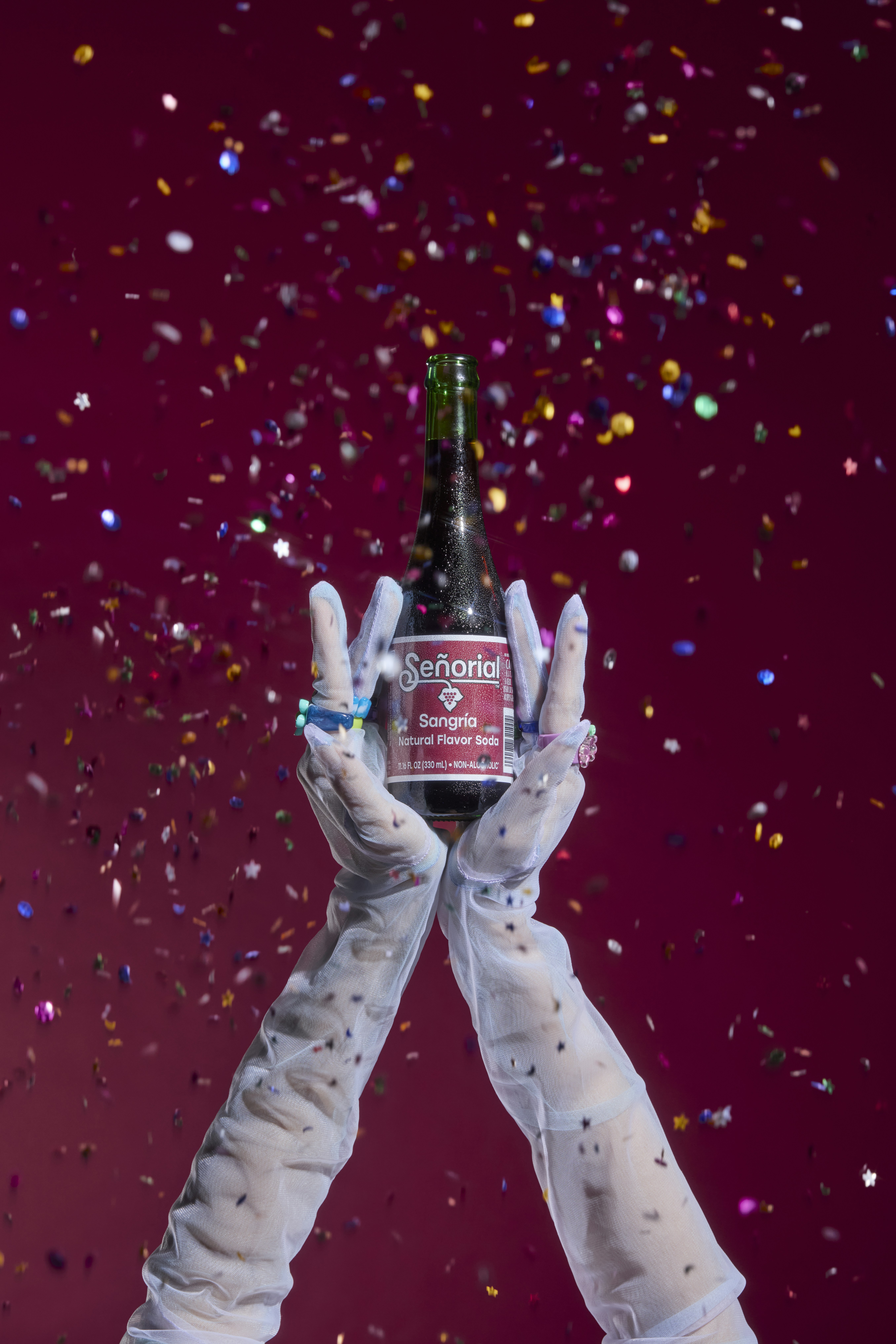 Le mani stringono una bottiglia di sangria con coriandoli.
