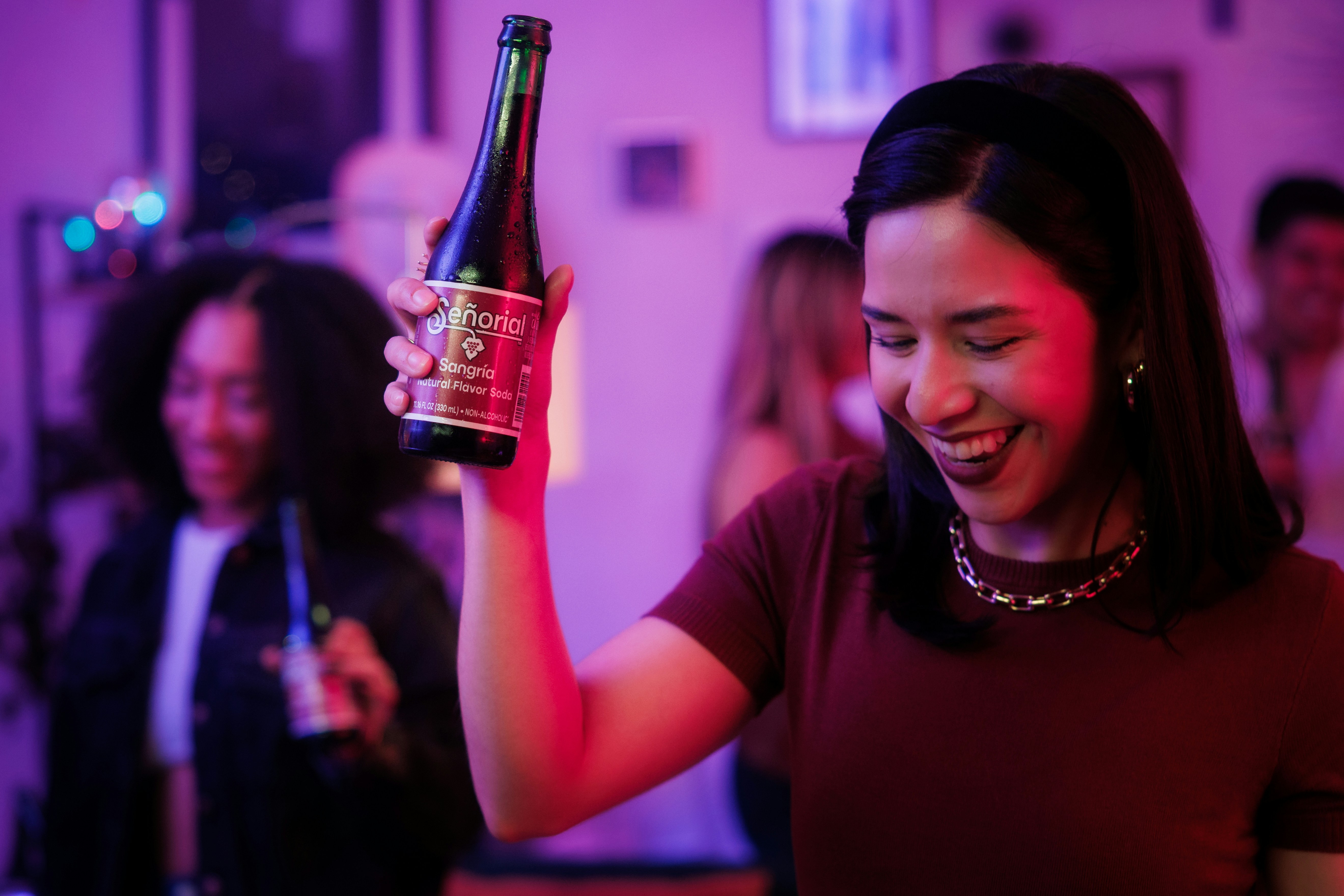 Woman is smiling while holding a bottle of wine.