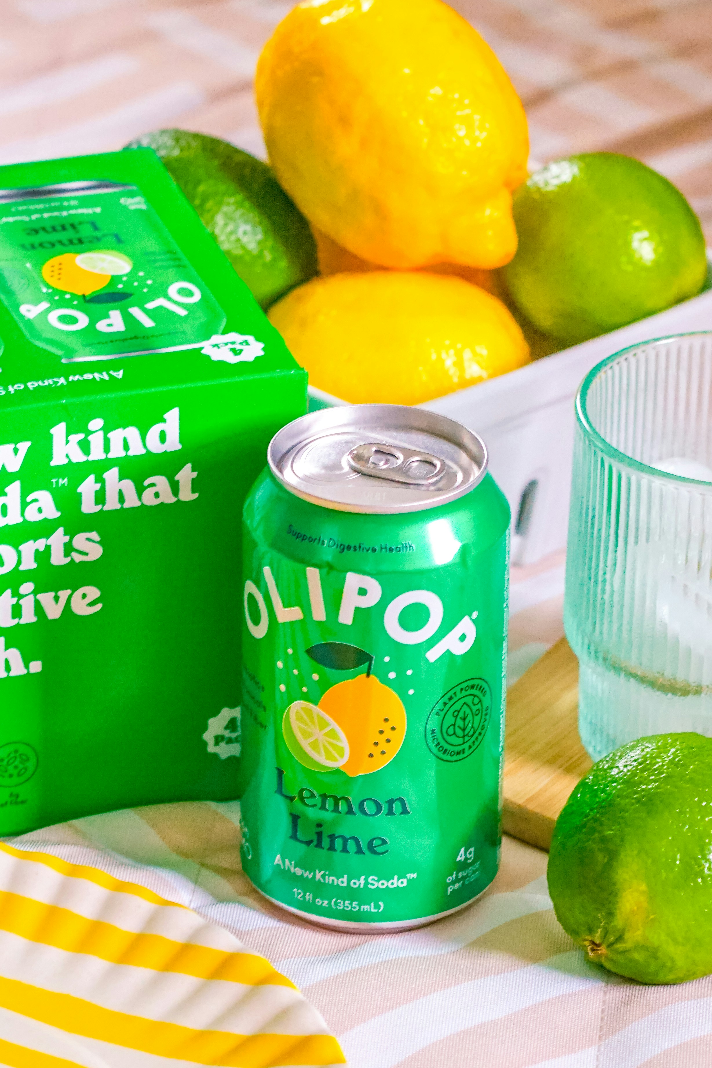 Olipop, soda al limone e lime, frutta fresca e un bicchiere.