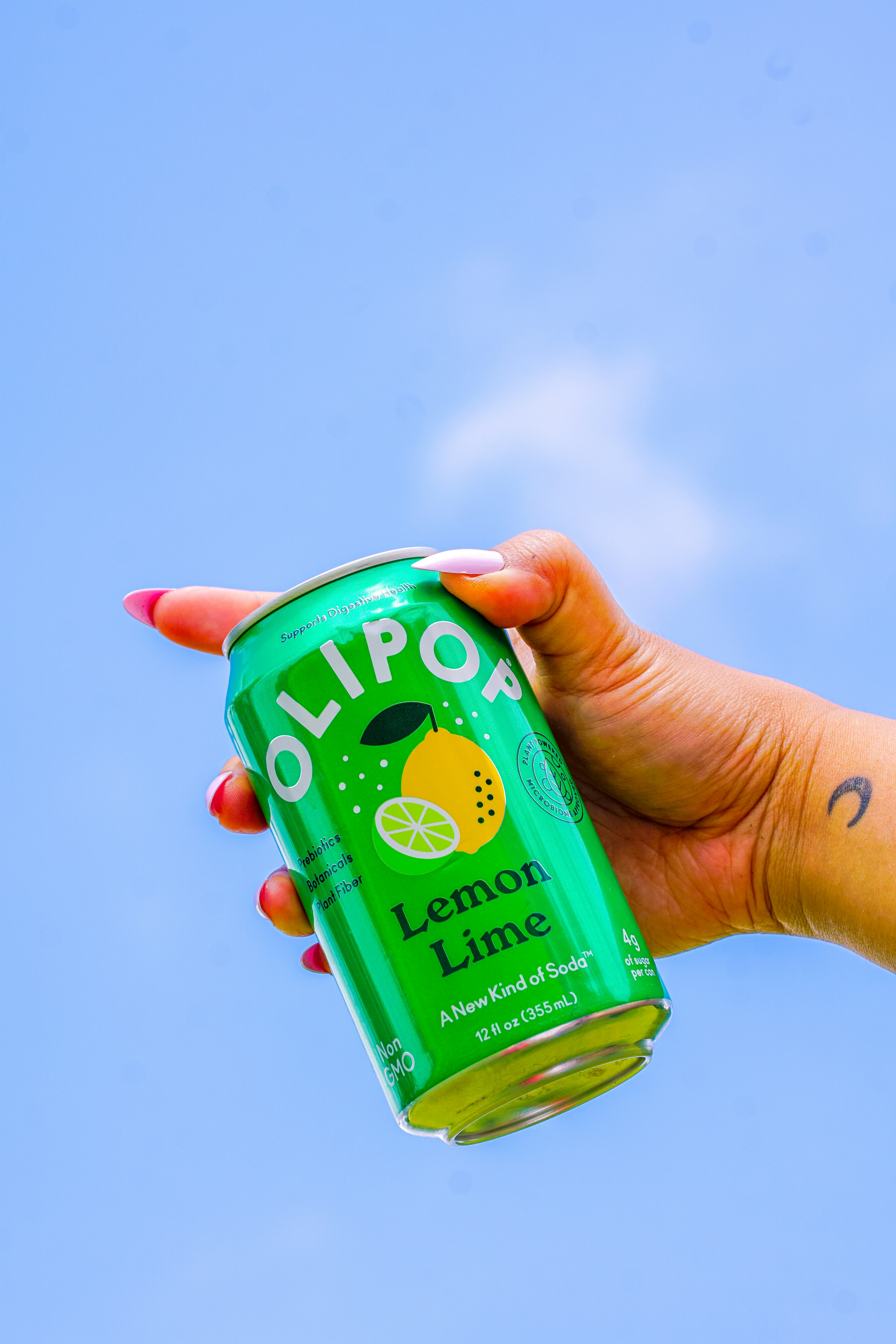 Una mano solleva una lattina di soda al limone e lime.