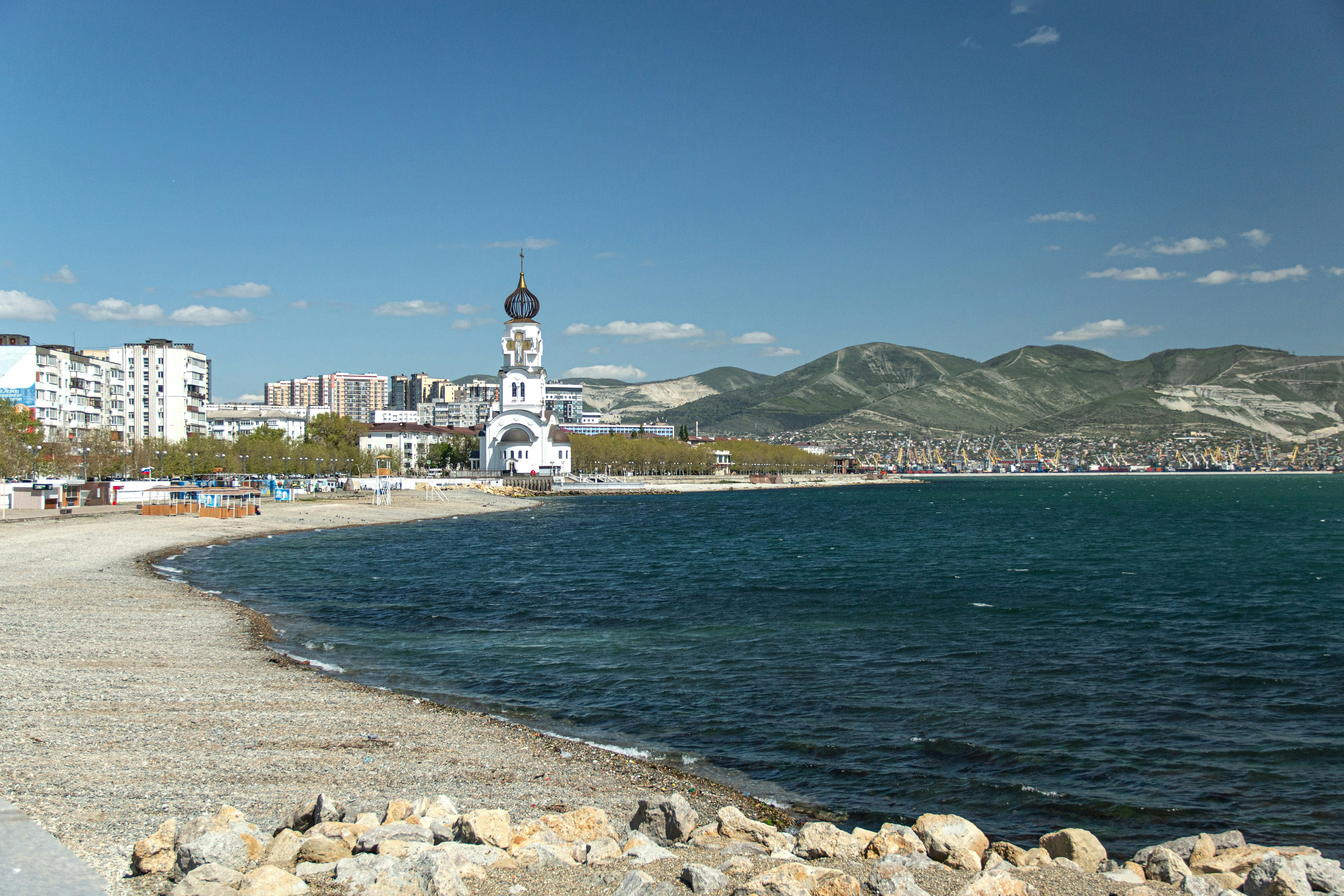 Beach scene with church and mountains in the background.