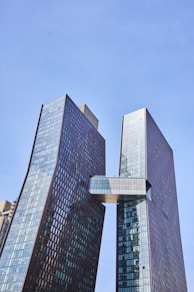Two modern skyscrapers connected by a bridge.