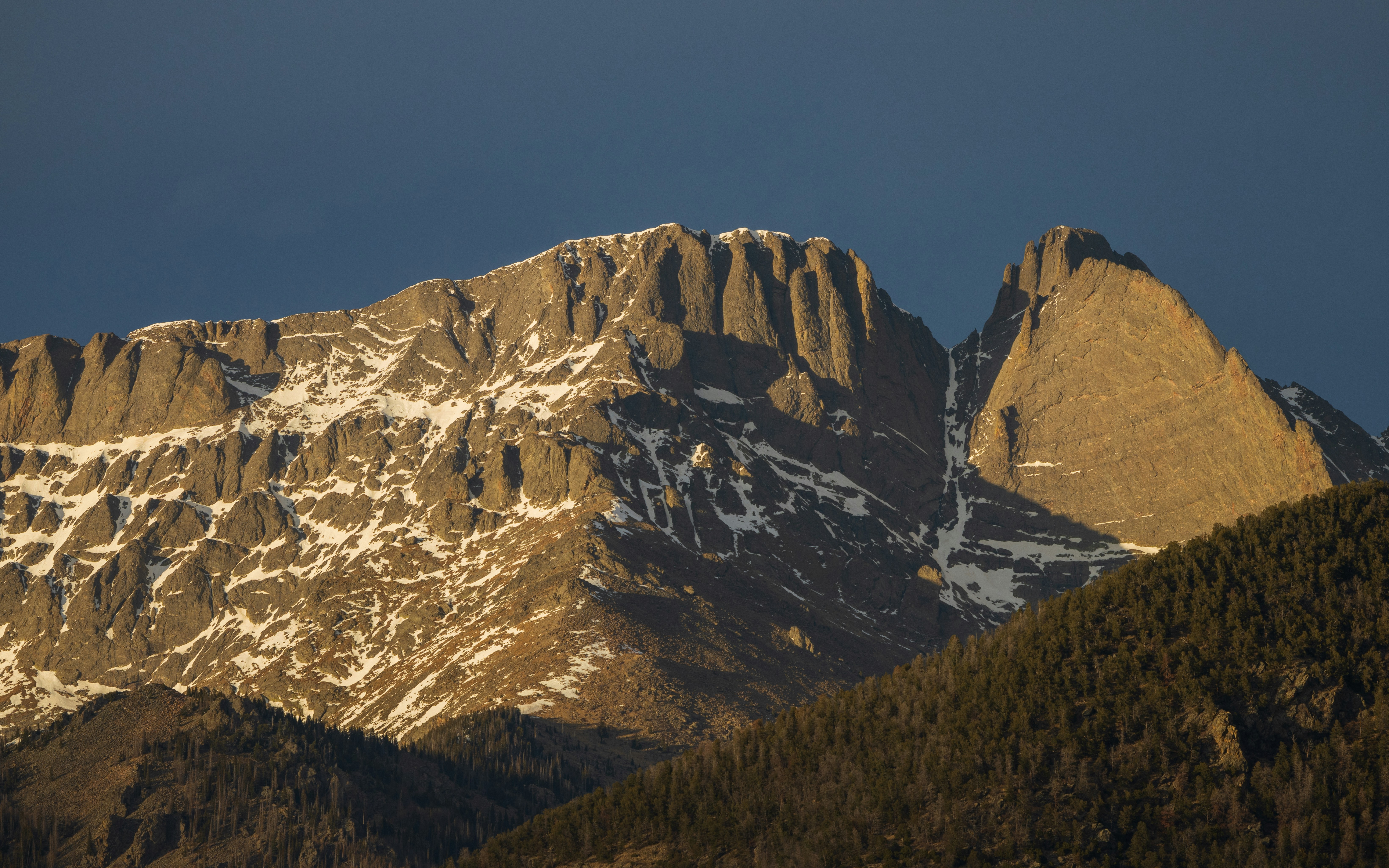 Snowy mountains stand against a dark blue sky.