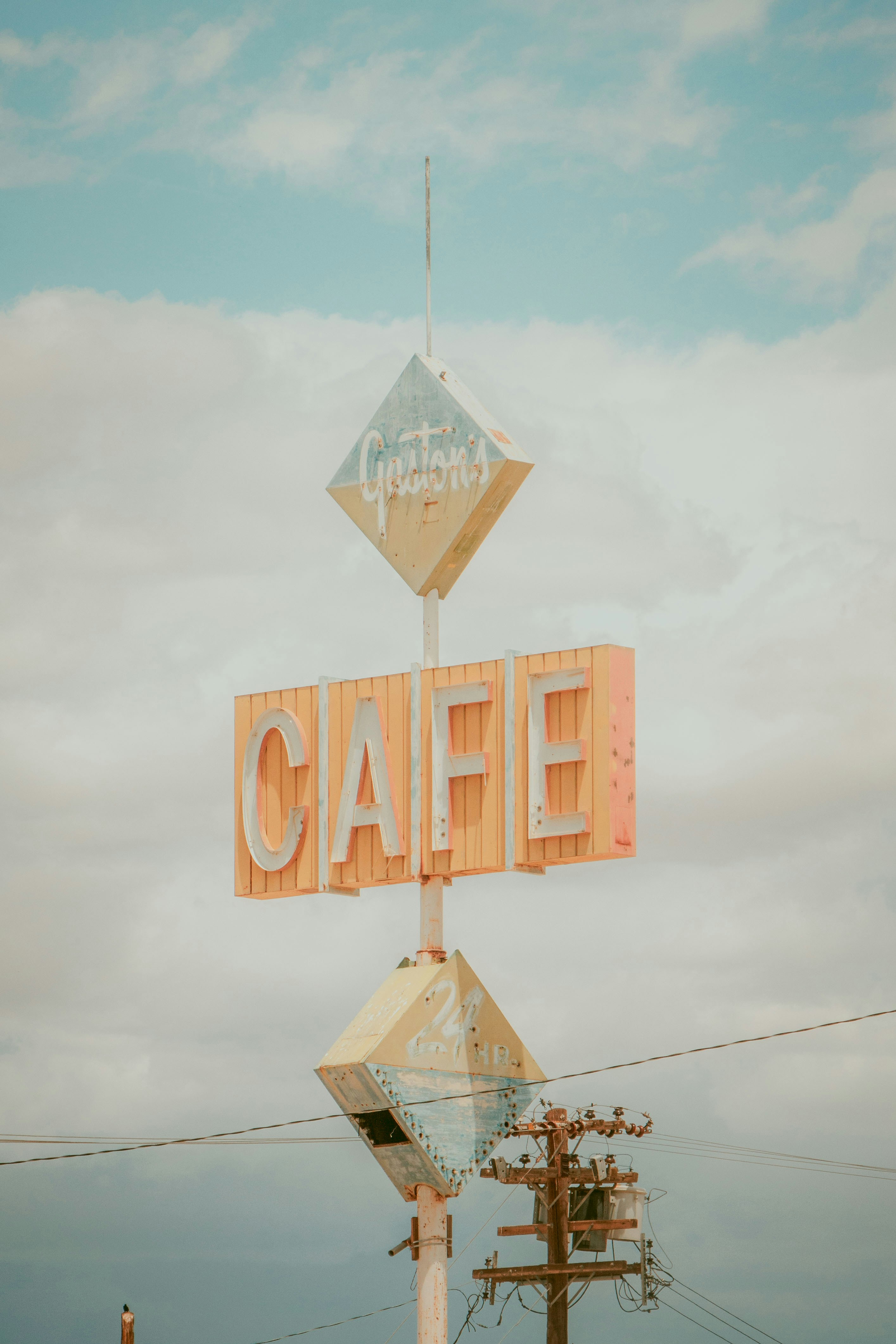 Una vecchia insegna di un caffè si erge sotto un cielo nuvoloso.