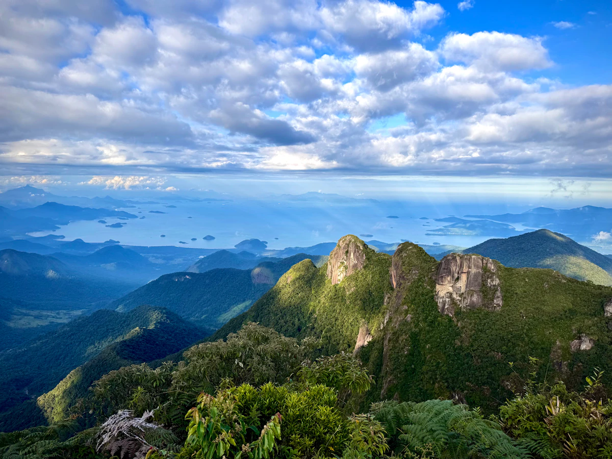 Vale com serras cobertas de mata sob céu azul