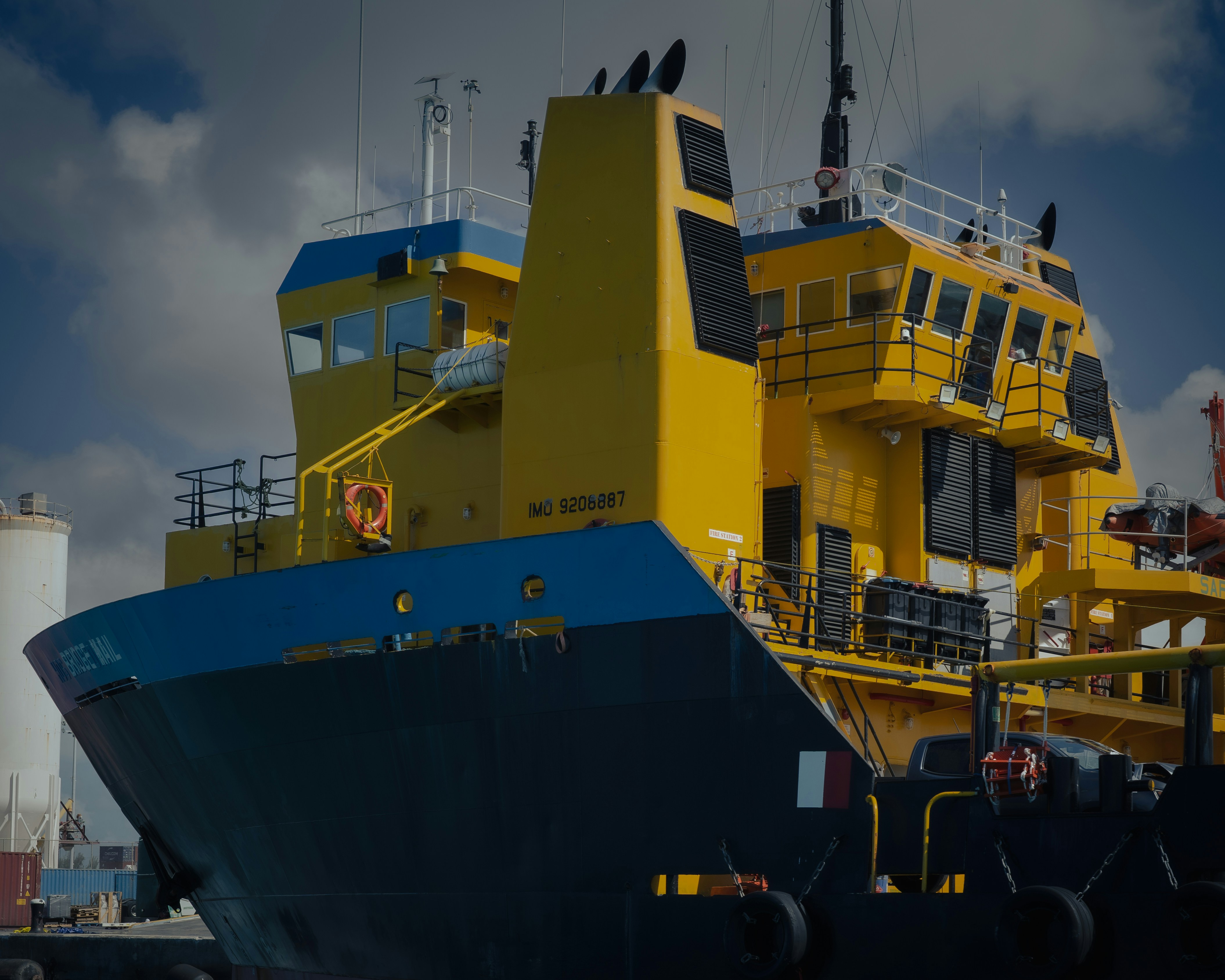 A bright yellow and blue ship rests in port.