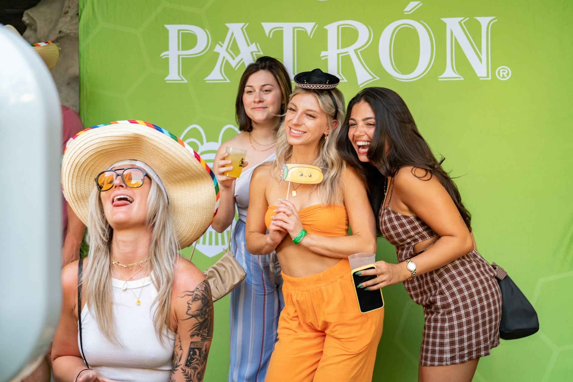 Friends pose happily in a photo booth with props.