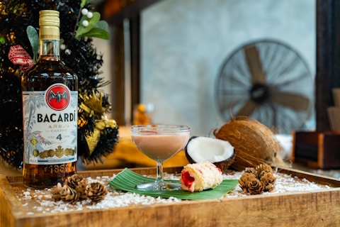 A bottle of bacardi, cocktail, and coconut.
