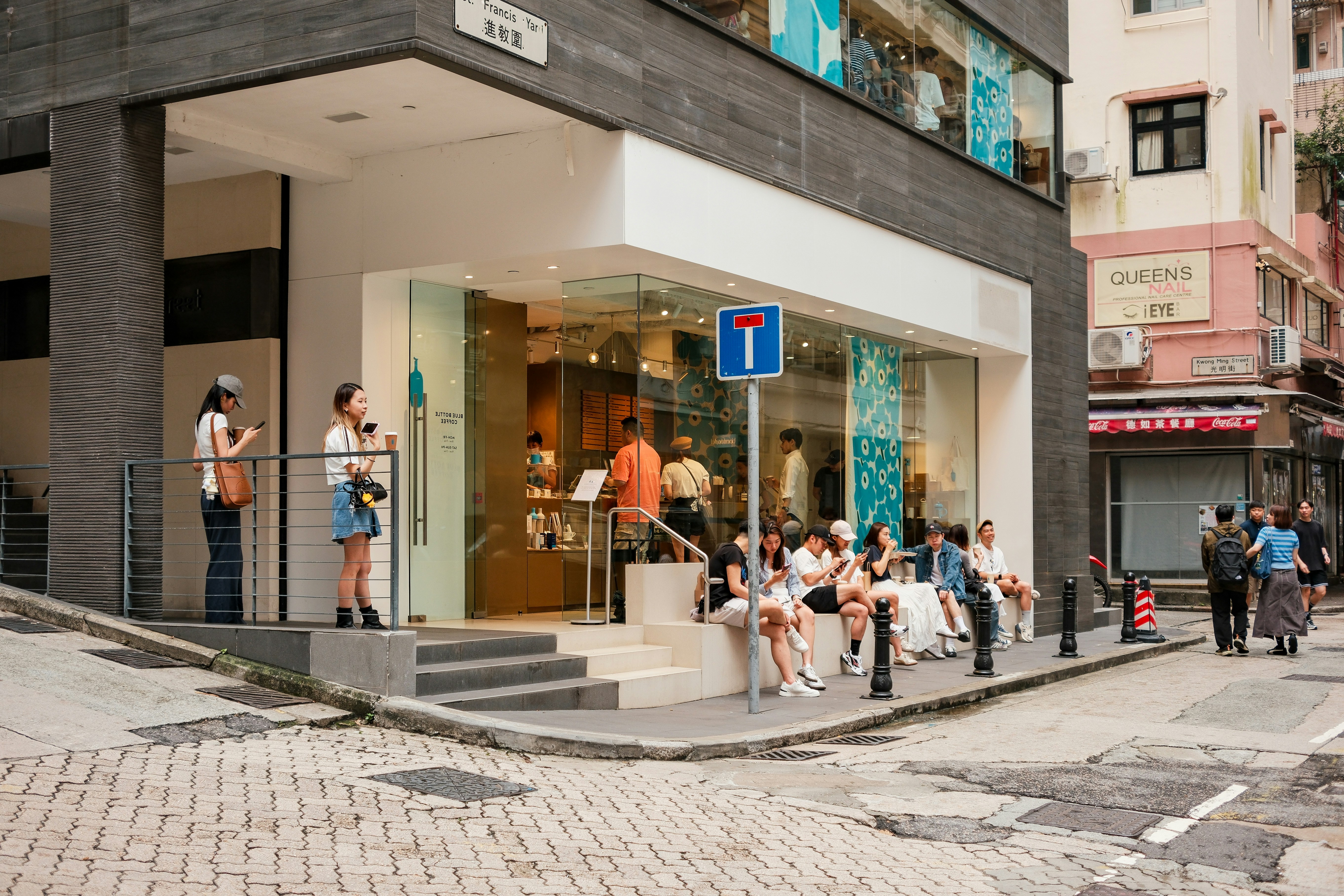 People gather outside a shop on a city street.