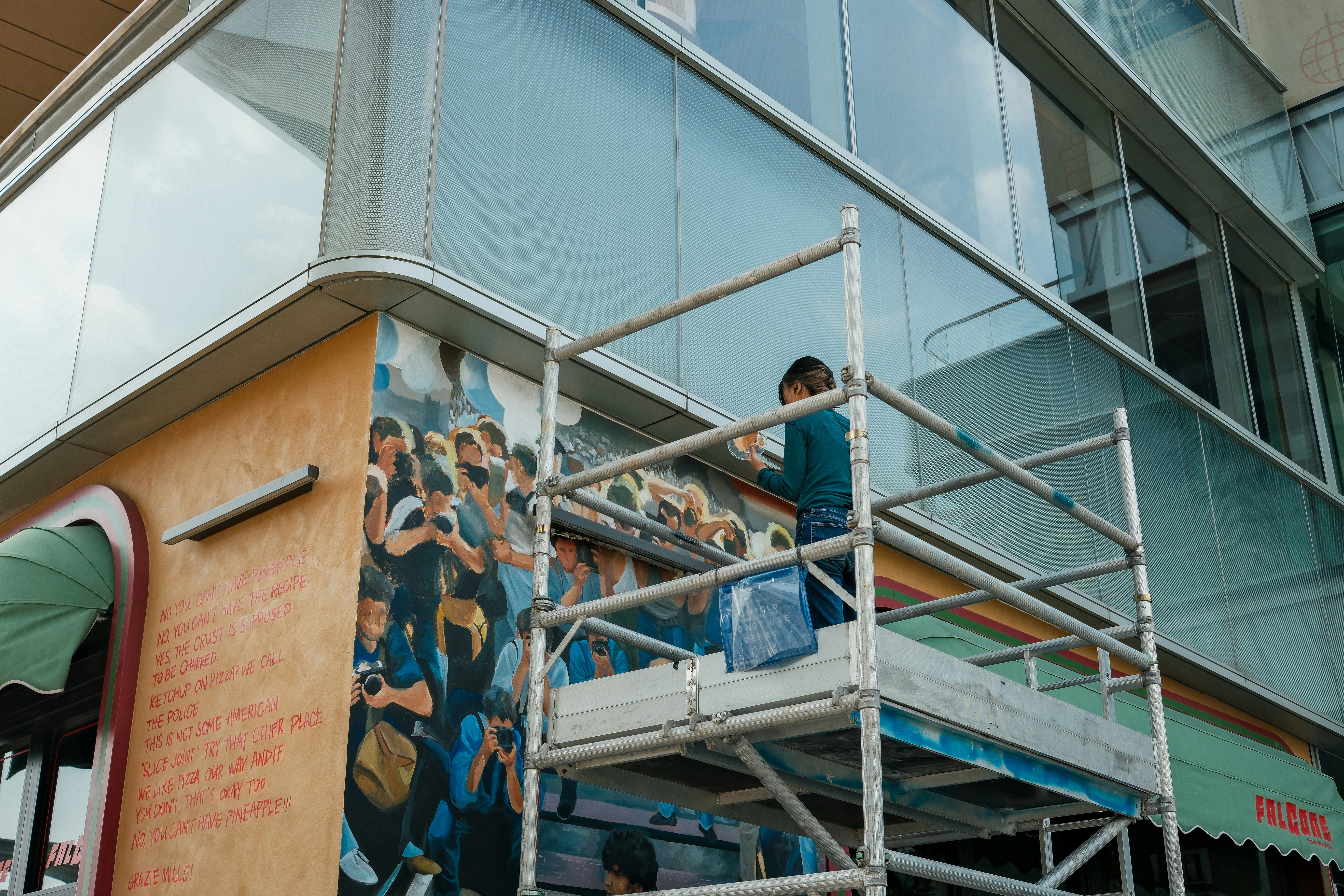 A person paints a mural on the side of a building.