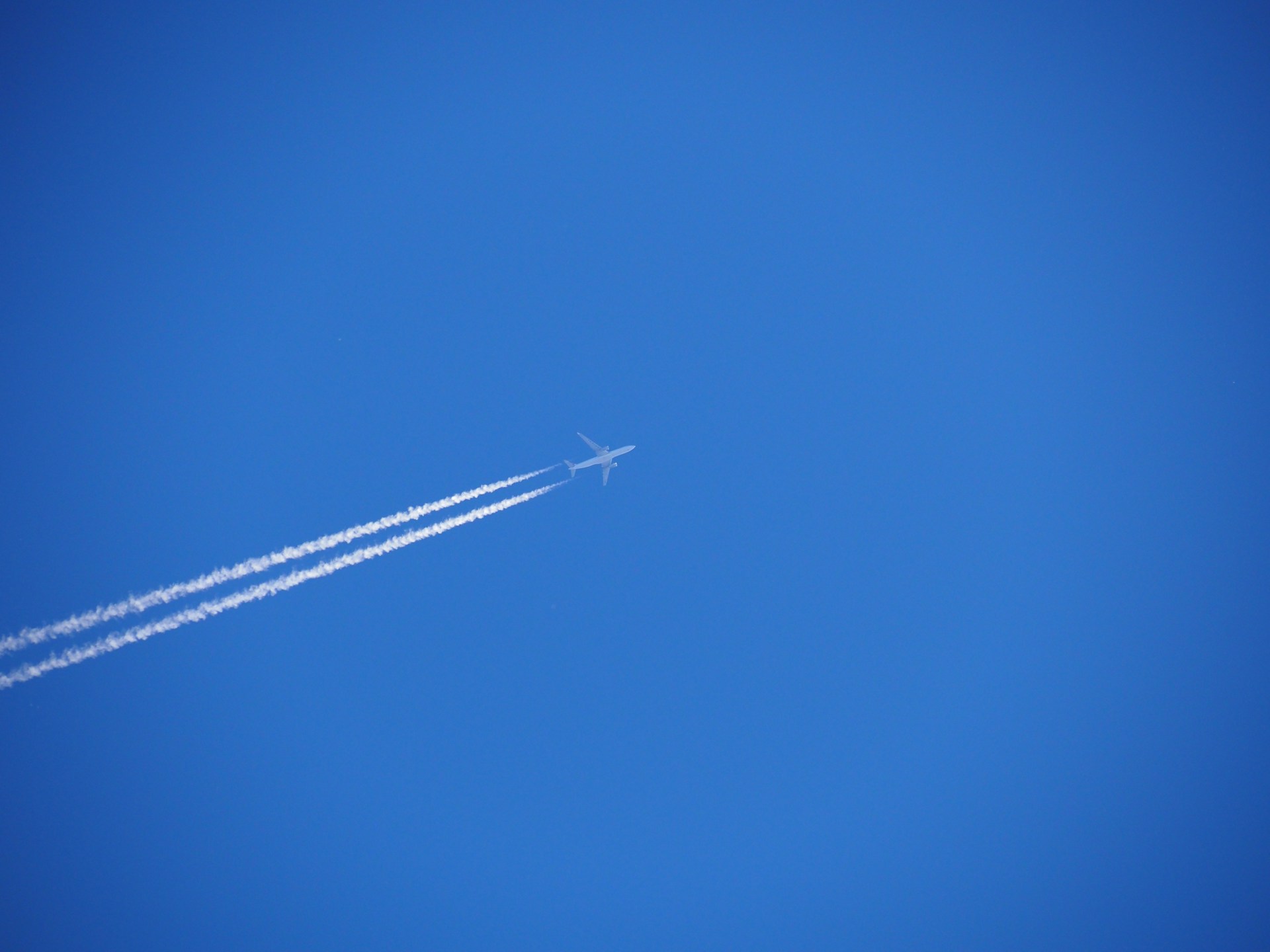 An airplane soars through the bright blue sky.