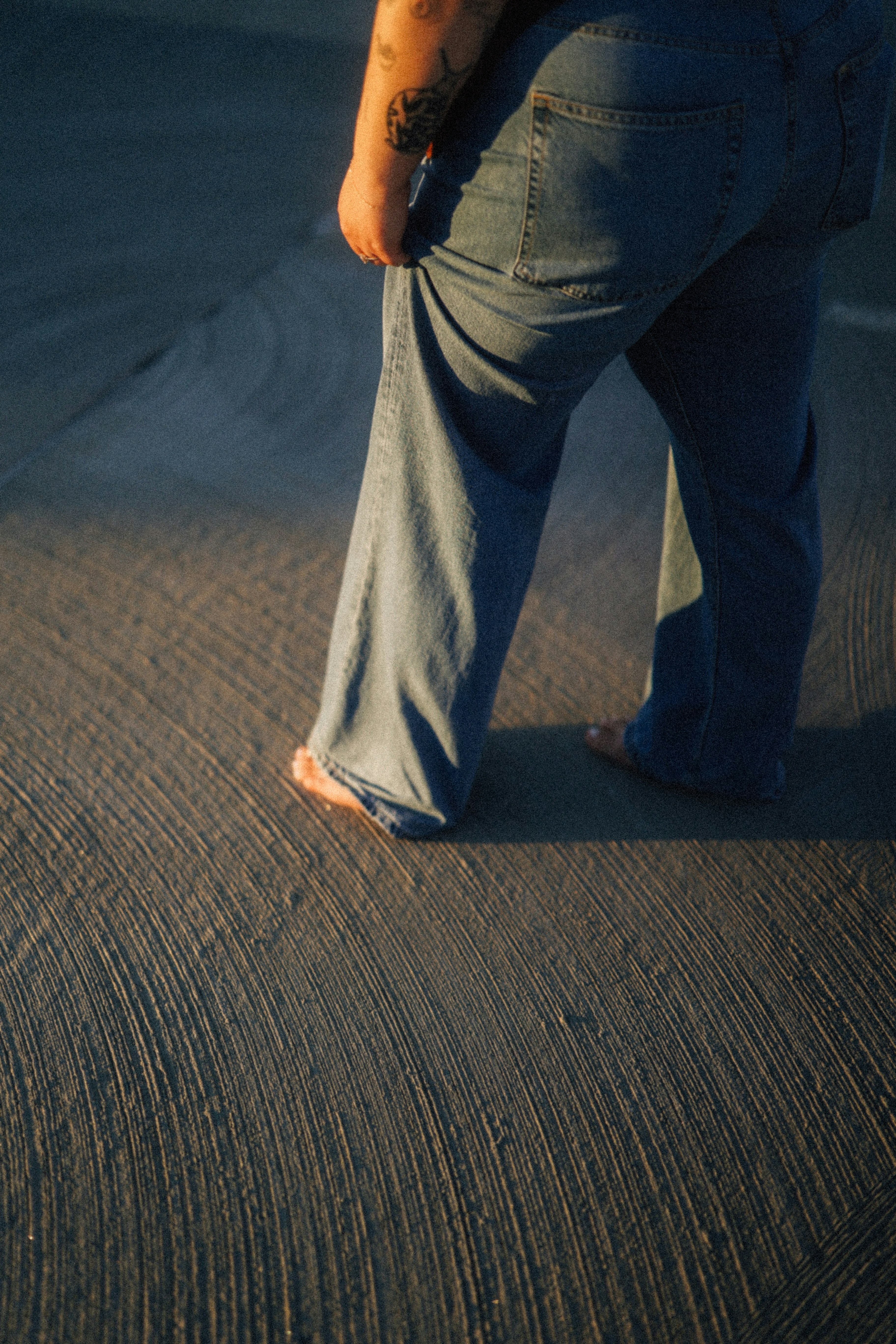 Person walks barefoot across textured concrete.