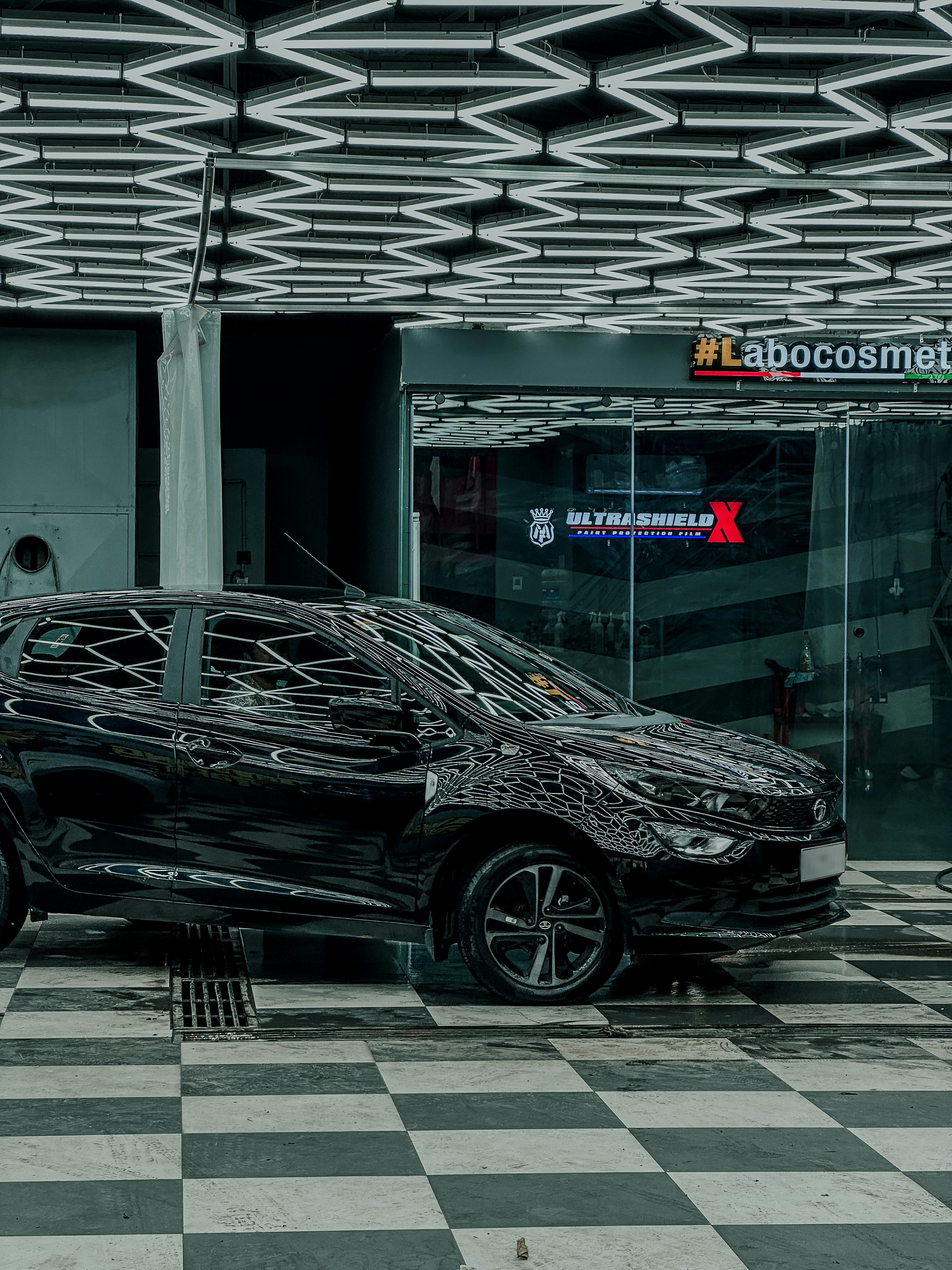 Glossy black vehicle inside a premium detailing studio