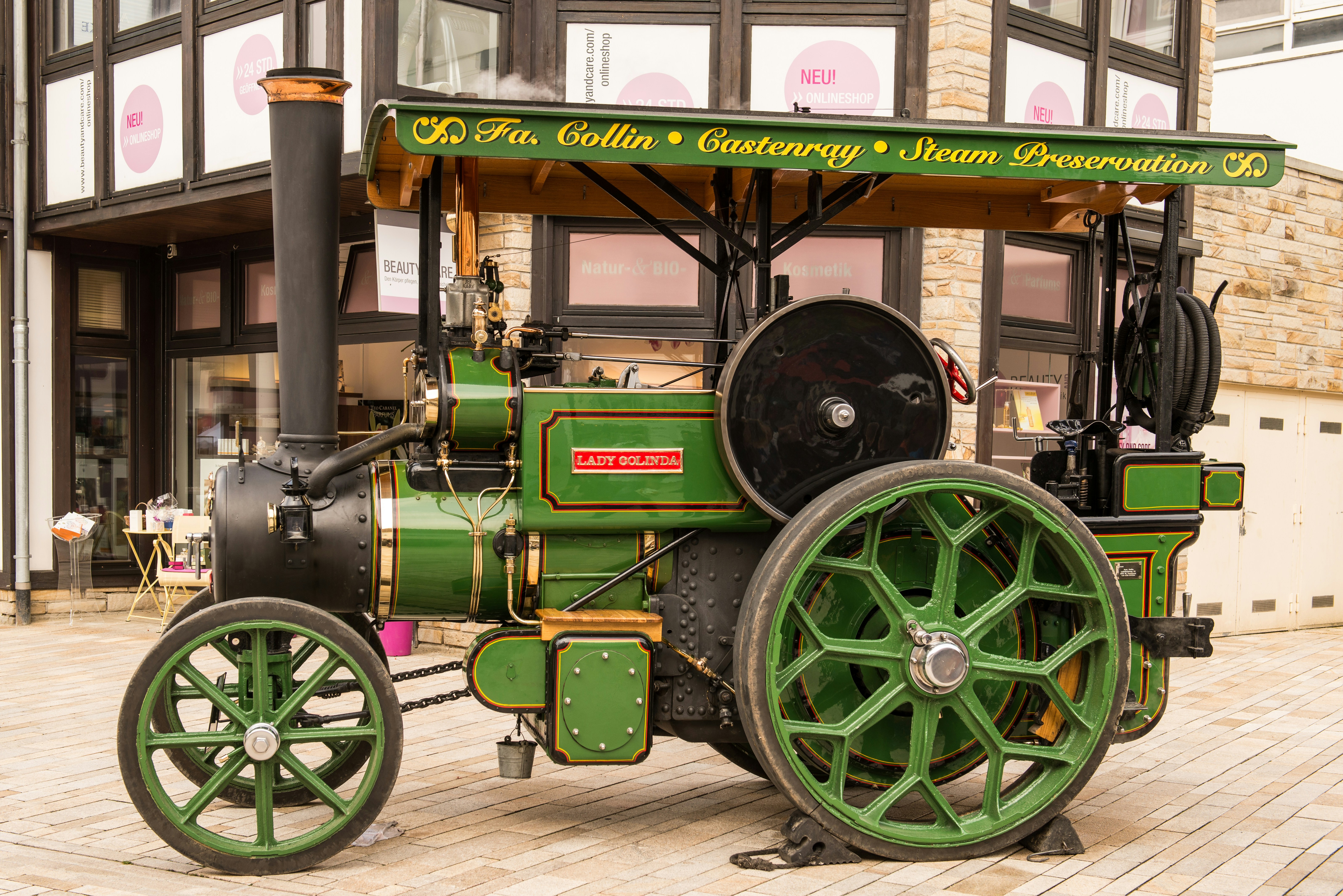 A green steam engine is prominently displayed outdoors.
