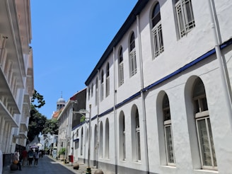 Buildings line a narrow street under a sunny sky.