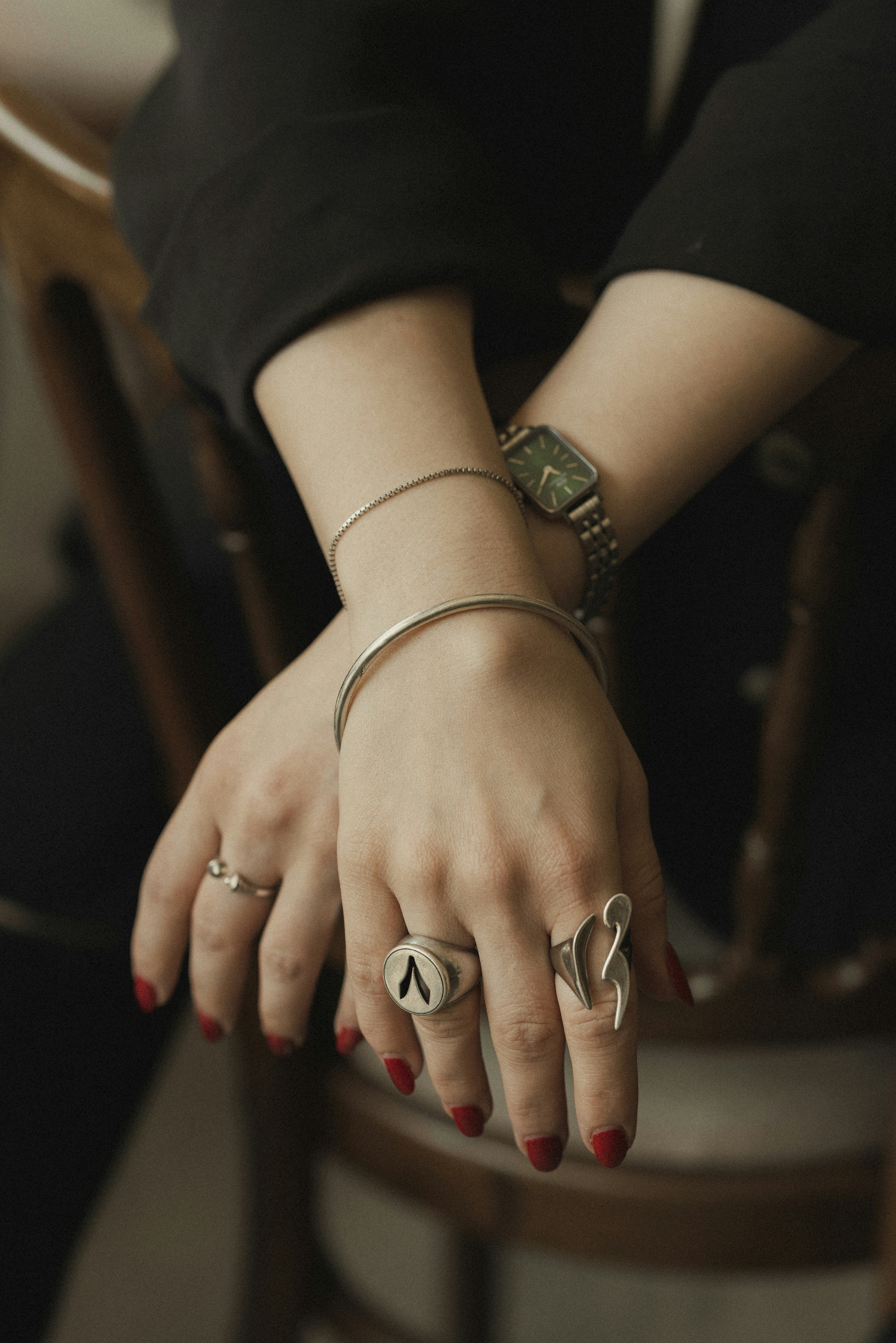 Hands show off jewelry and a watch.