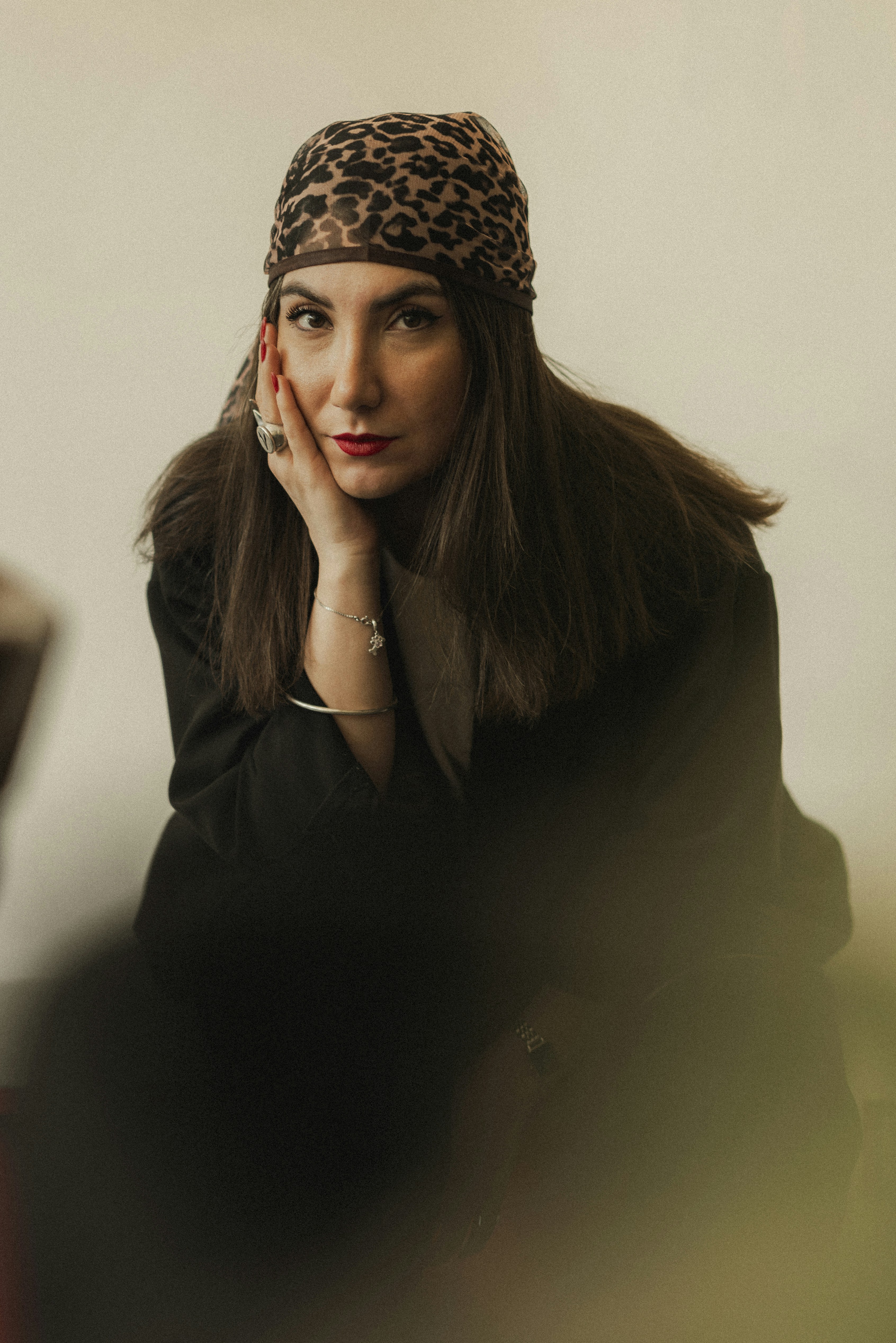 A woman poses, wearing a leopard-print headscarf.