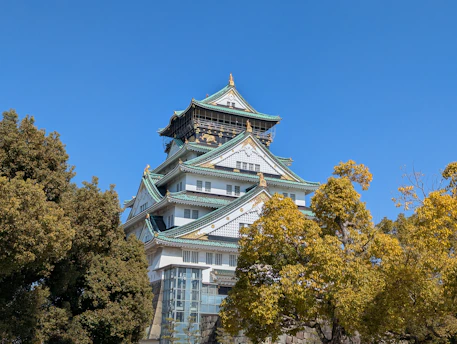 Osaka castle stands tall against a blue sky.
