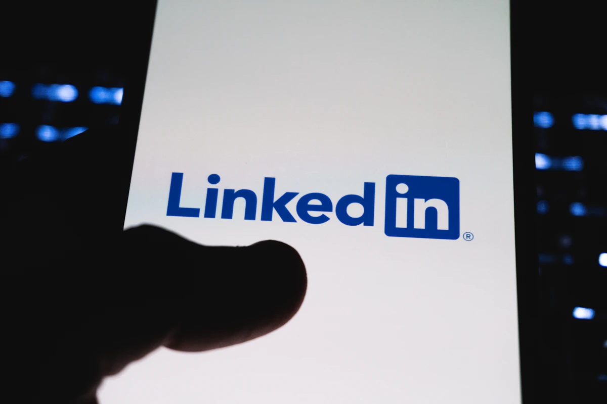 Person pointing at LinkedIn logo on smartphone