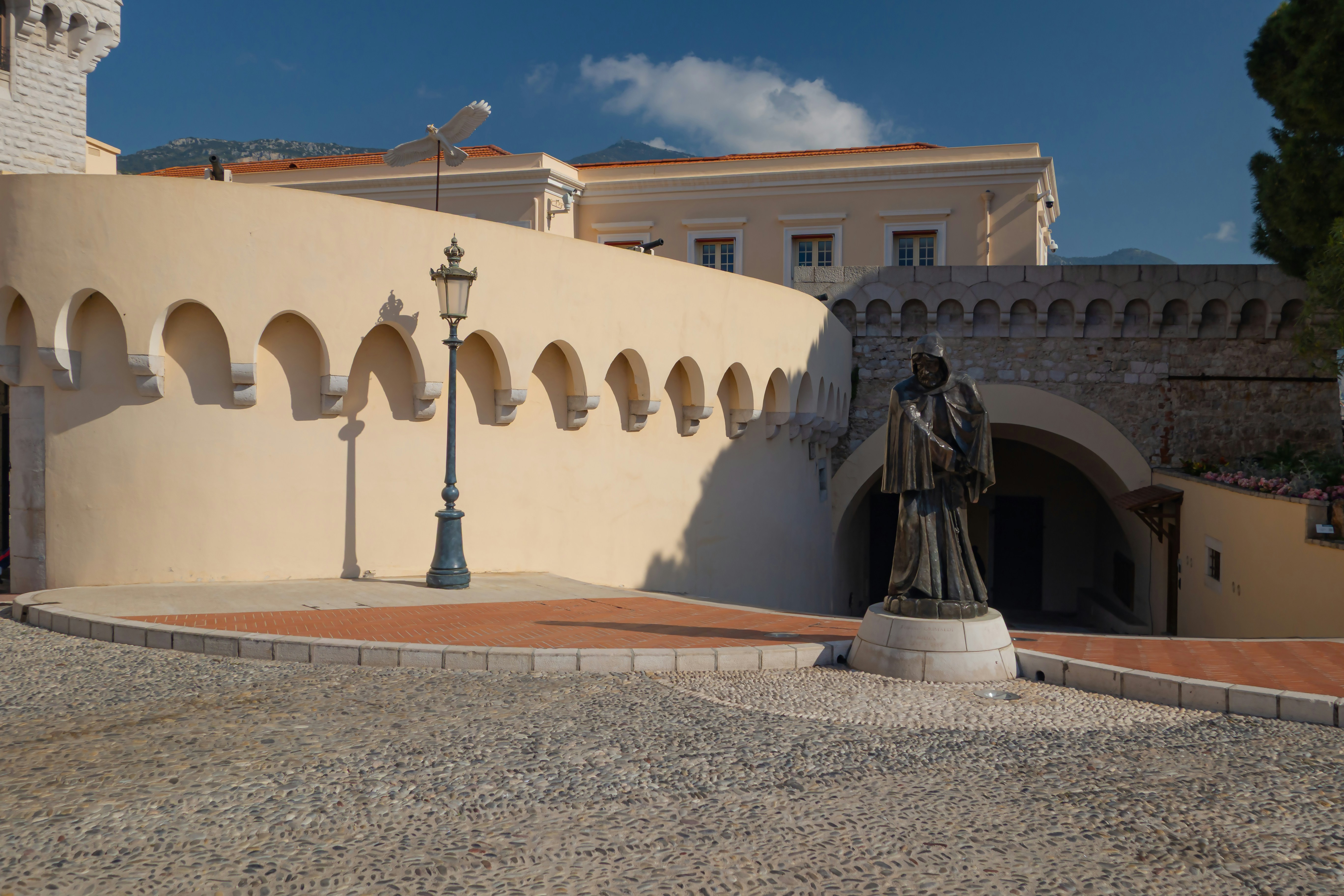 A statue sits near a building with arches.