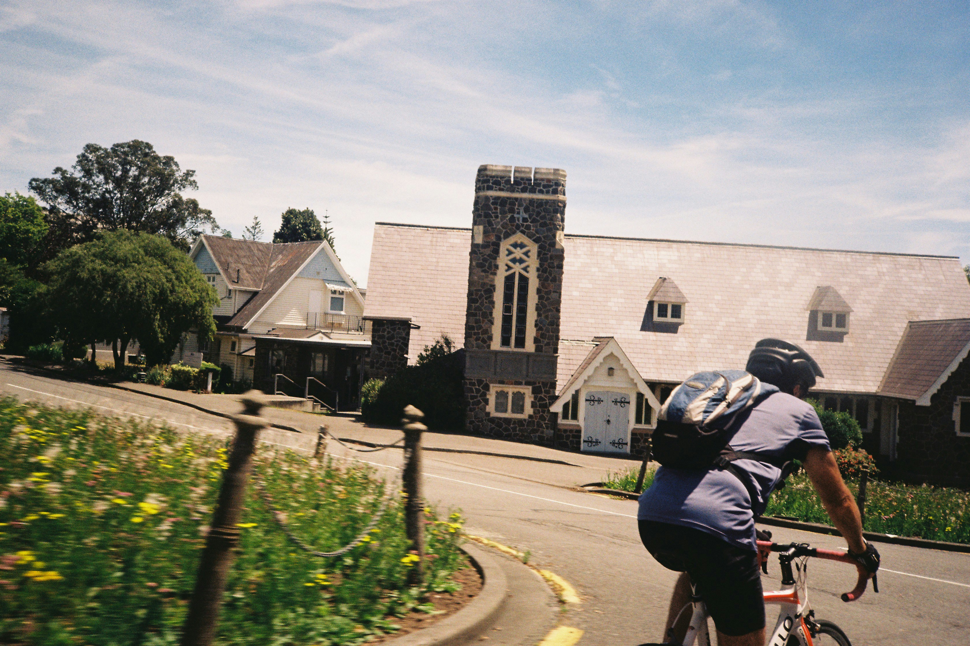 A cyclist rides past a church and houses.