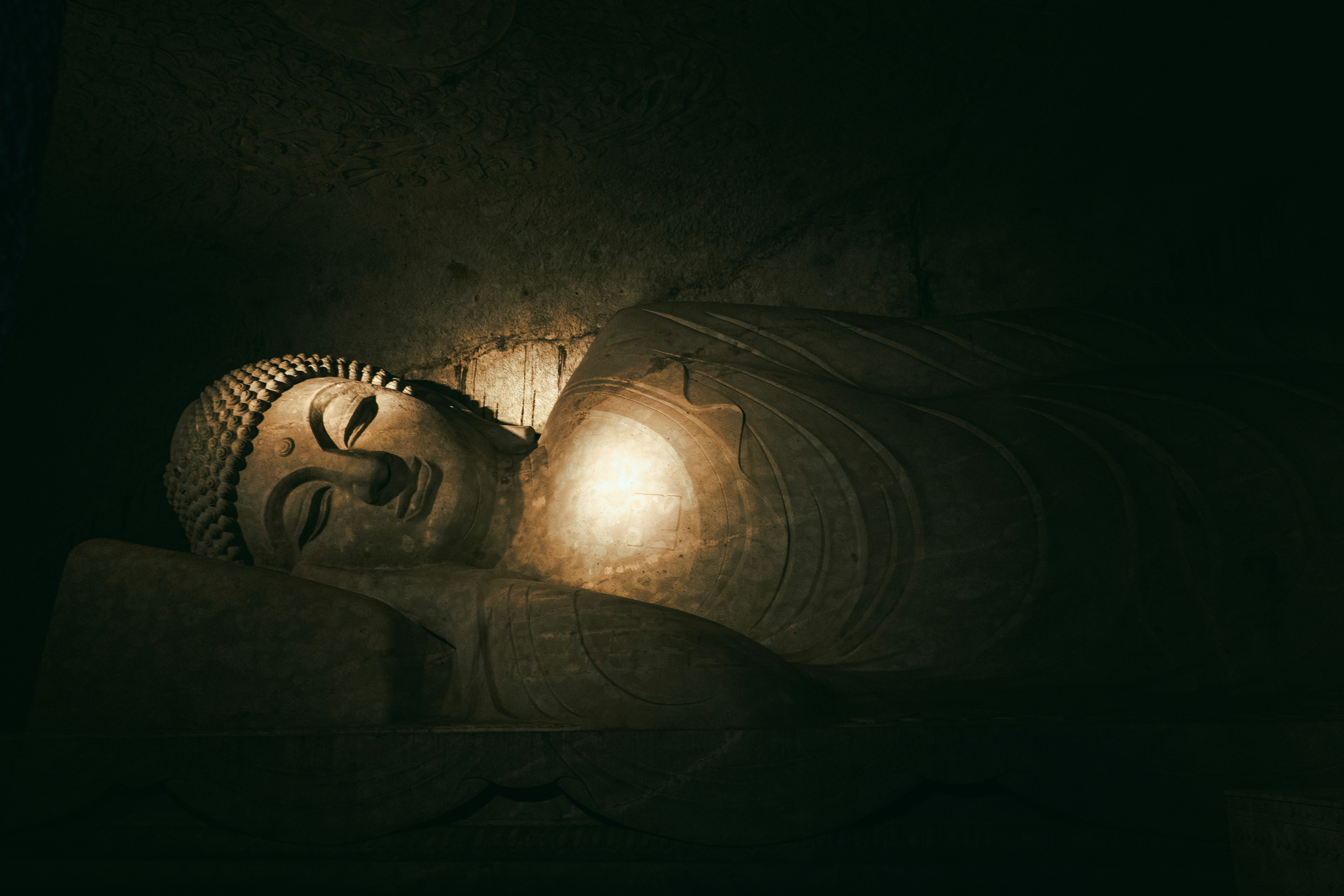 Sleeping buddha statue illuminated in darkness.
