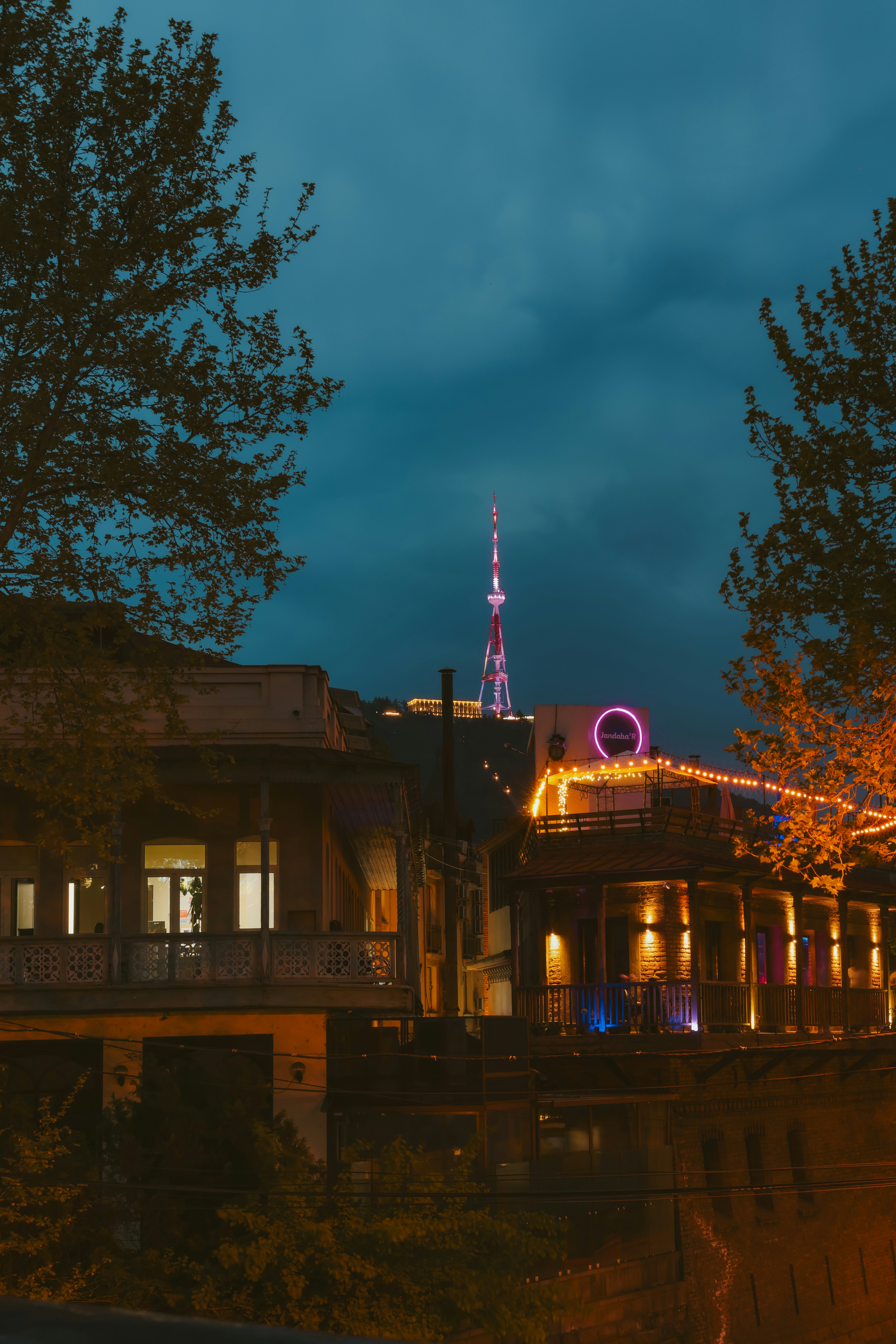 Cityscape at night with illuminated buildings and tower.