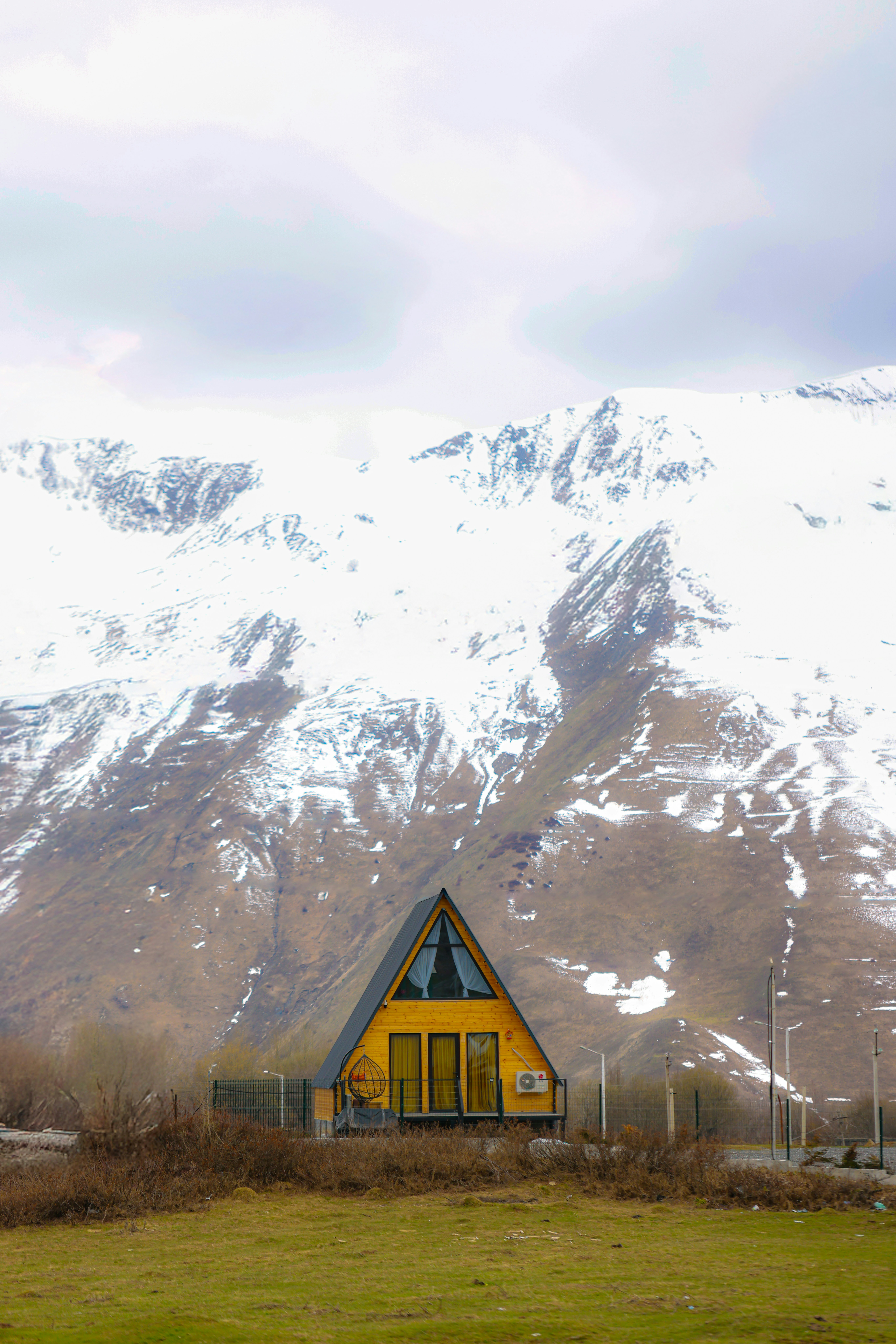 A-frame cabin sits before snow-capped mountains.