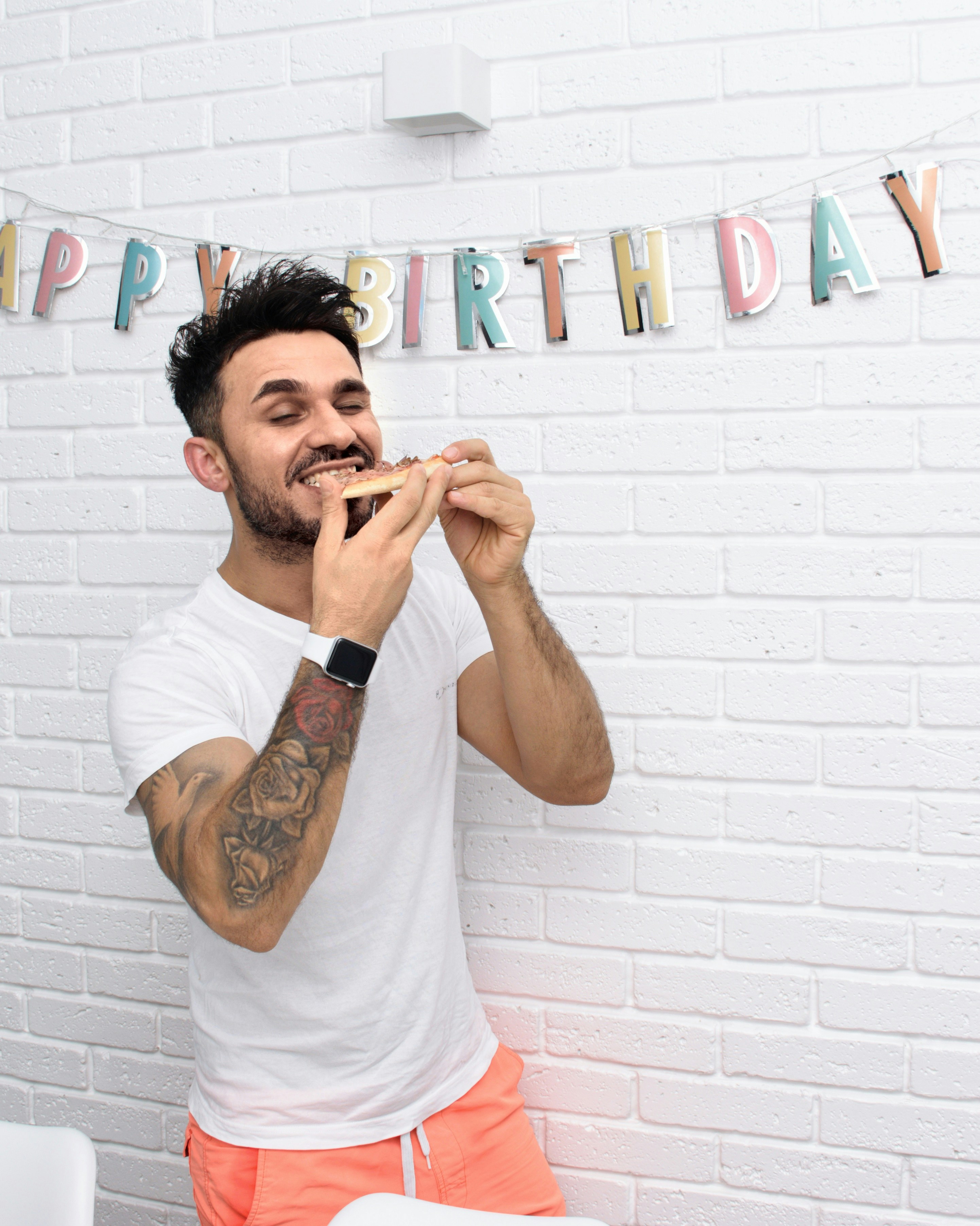 Man happily eats pizza on his birthday.