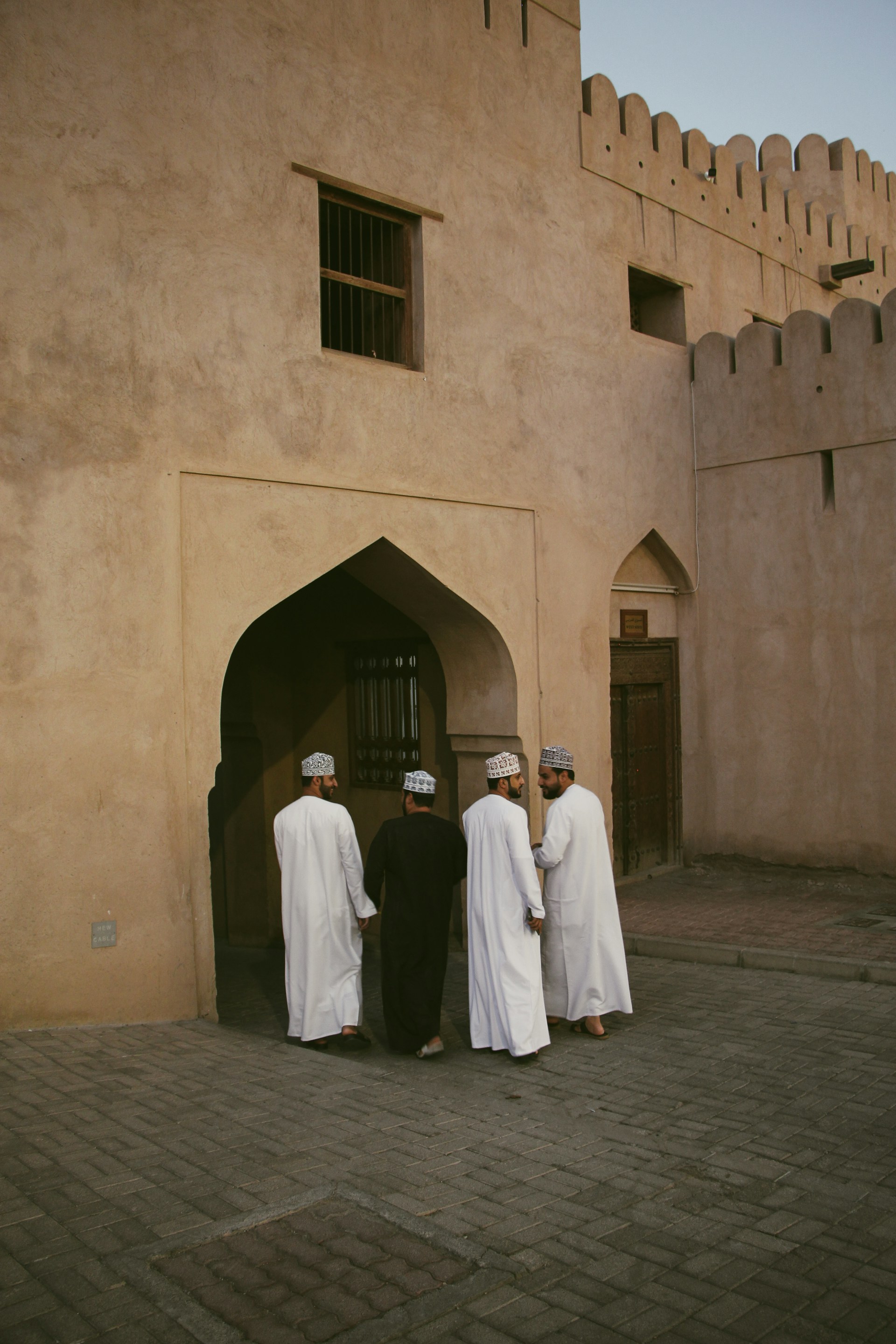 Men in traditional attire stand by an archway.