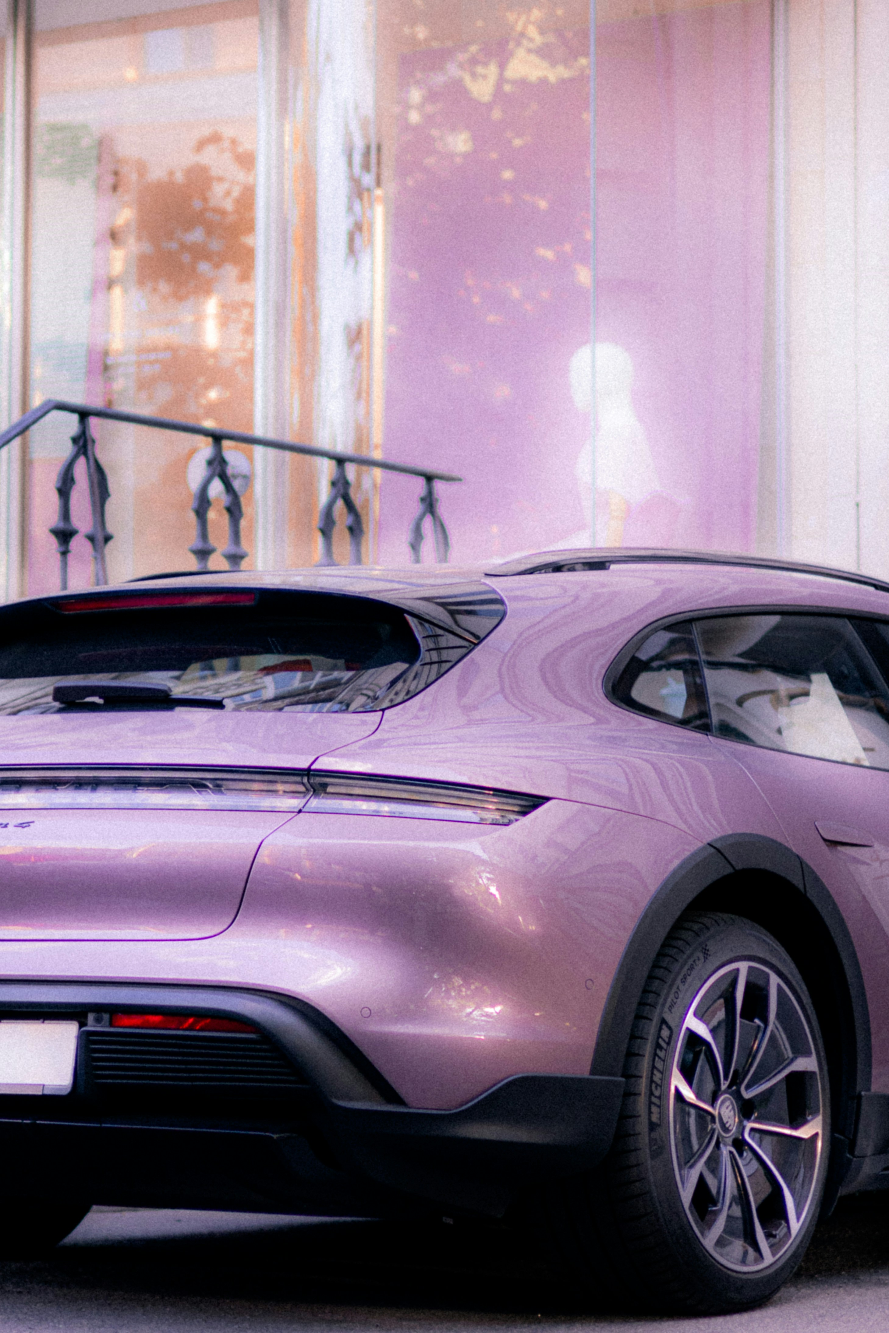 A pink car is parked near a building.