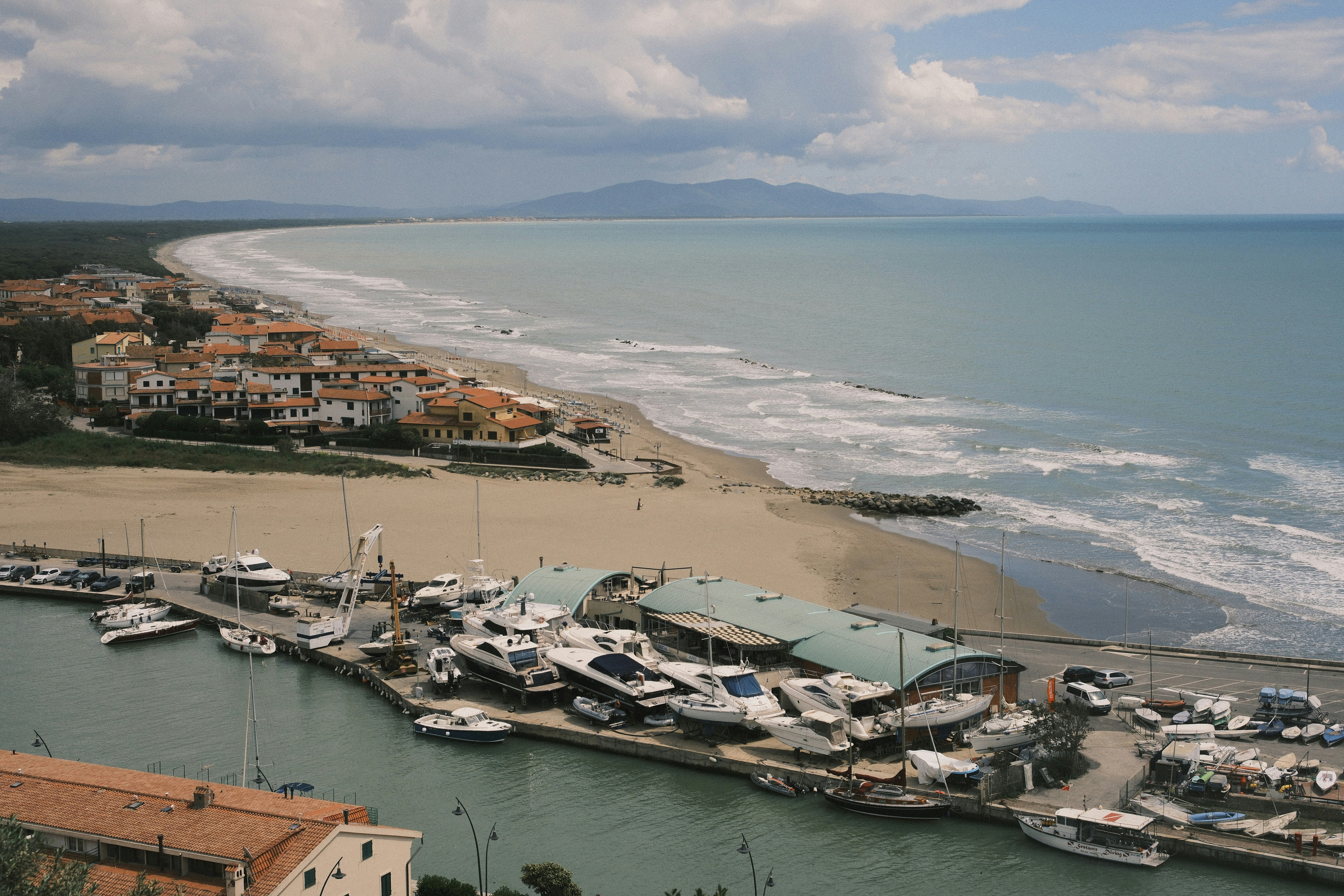 Boats and coastline under a partly cloudy sky.