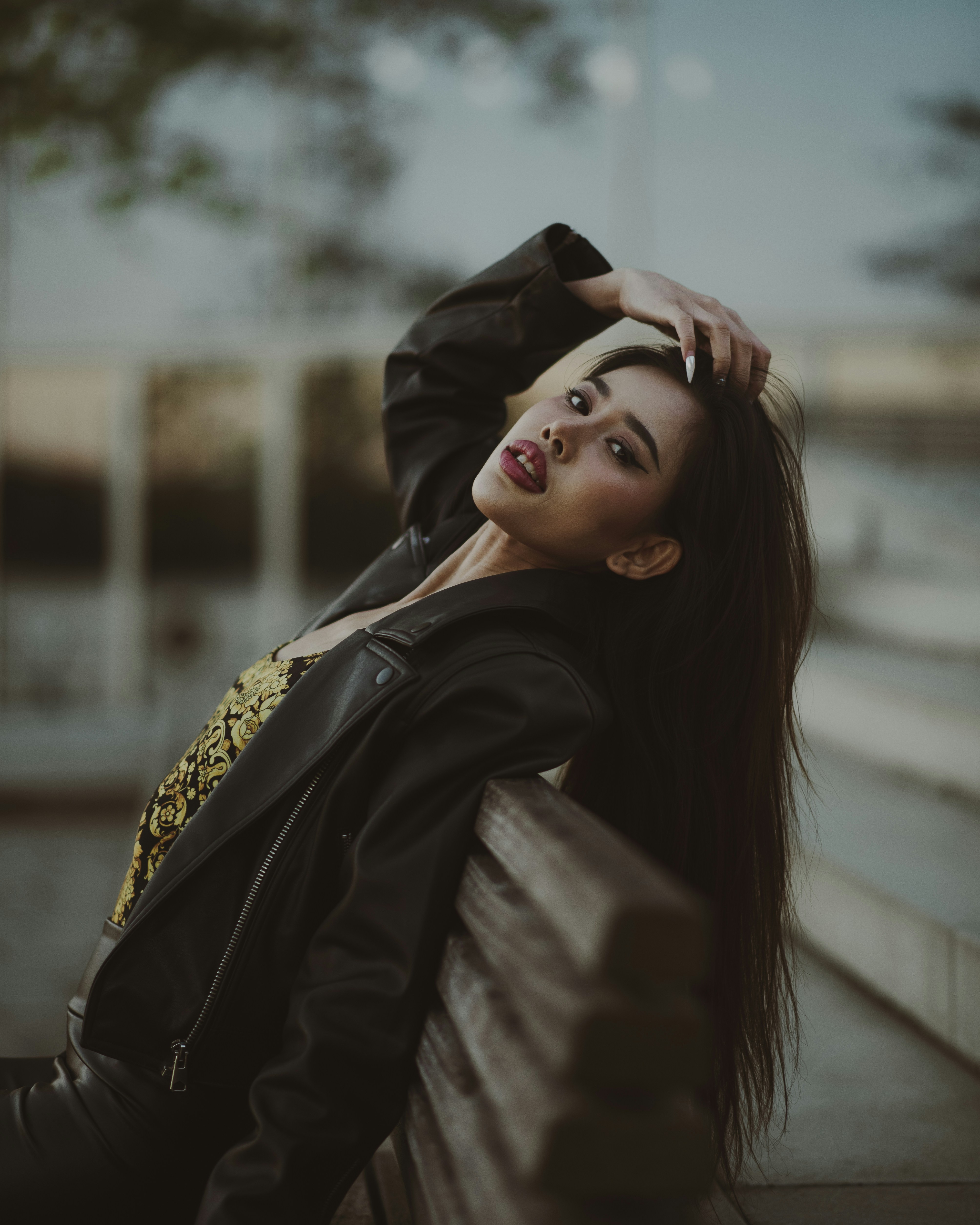 A fashionable woman poses against a blurred backdrop.