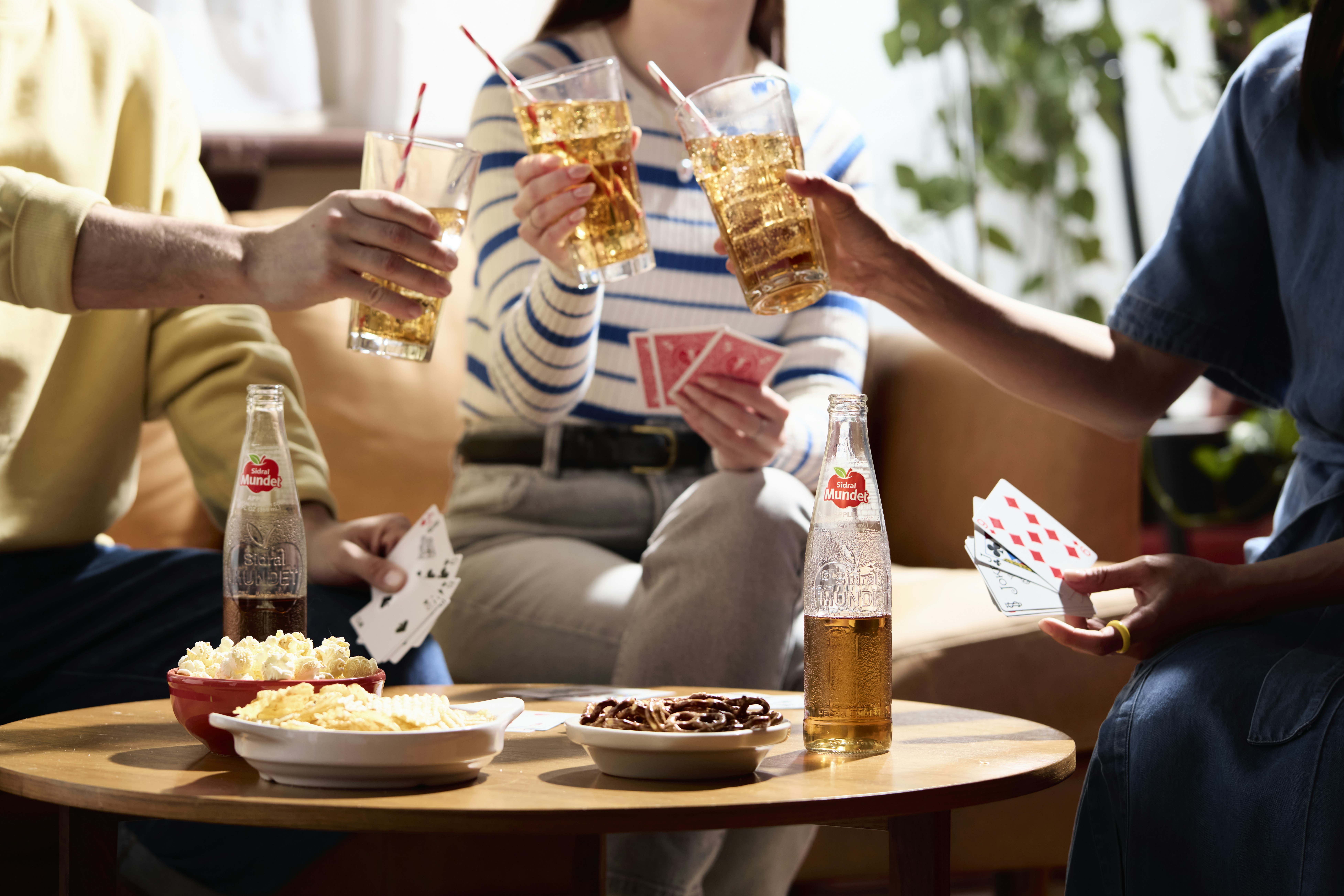 Friends are playing cards and enjoying drinks together.