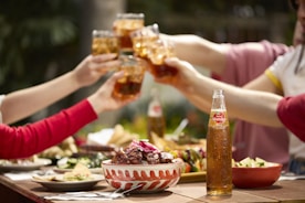 People toast with drinks at an outdoor meal.