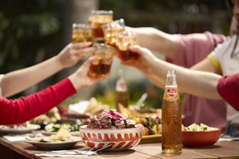 People toast with drinks at an outdoor meal.