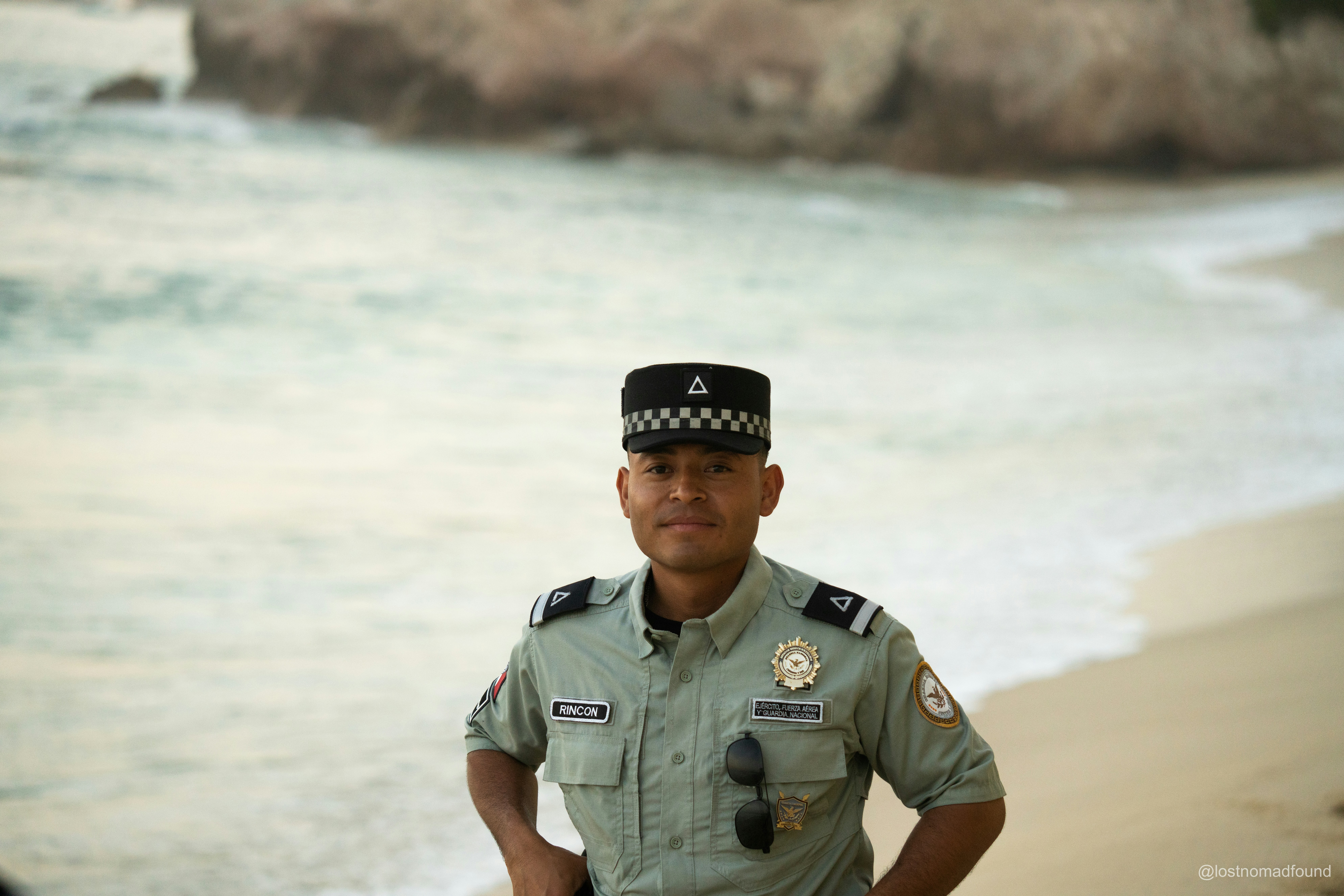 A security guard poses on a beach.
