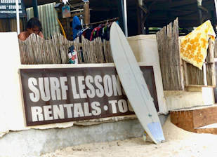 Surfboard leans against a "surf lessons" sign.