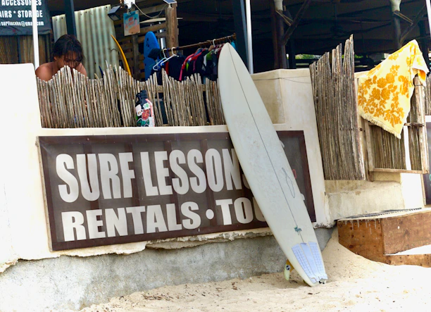 Surfboard leans against a "surf lessons" sign.