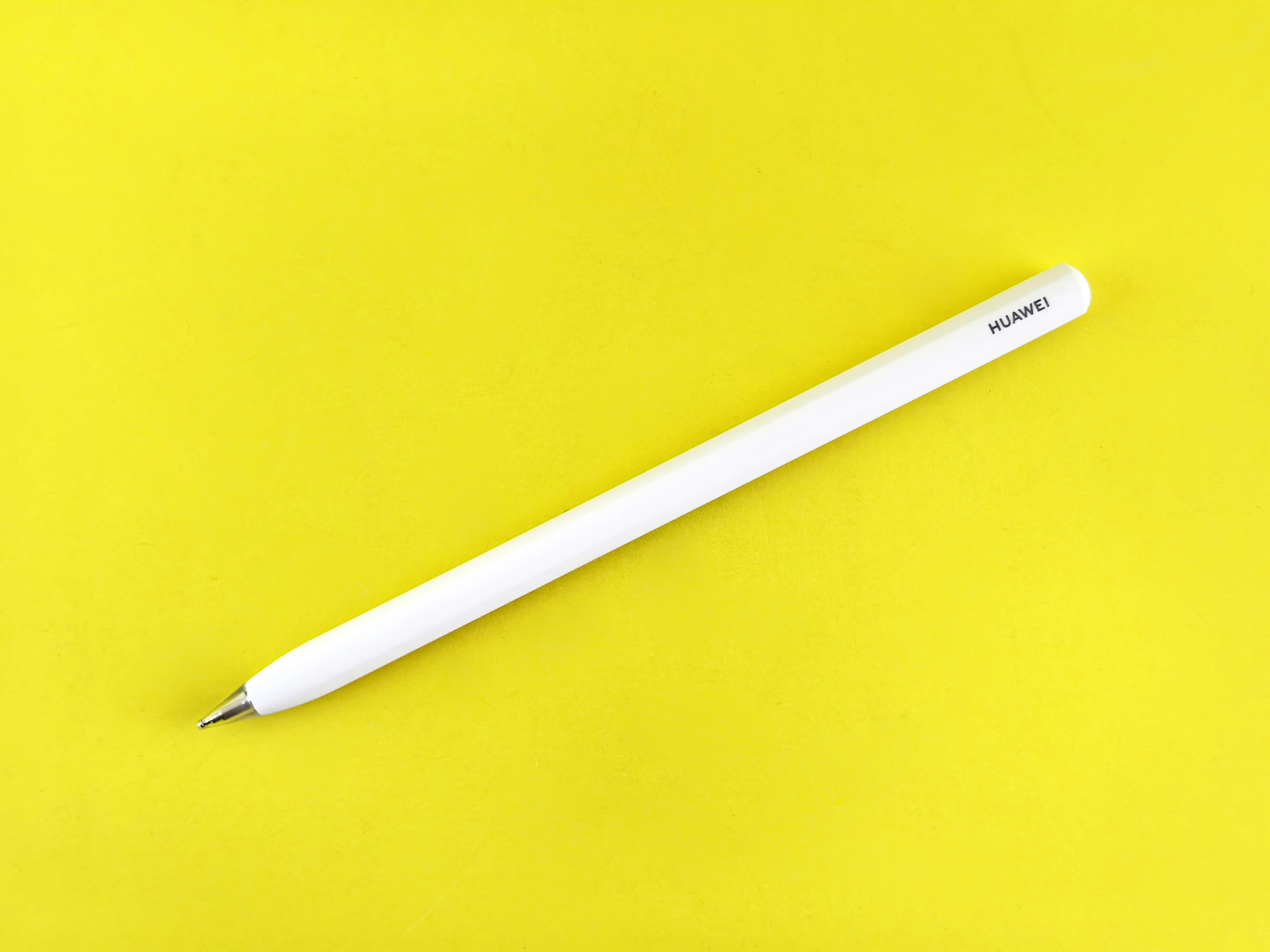 A white stylus pen rests on yellow background.