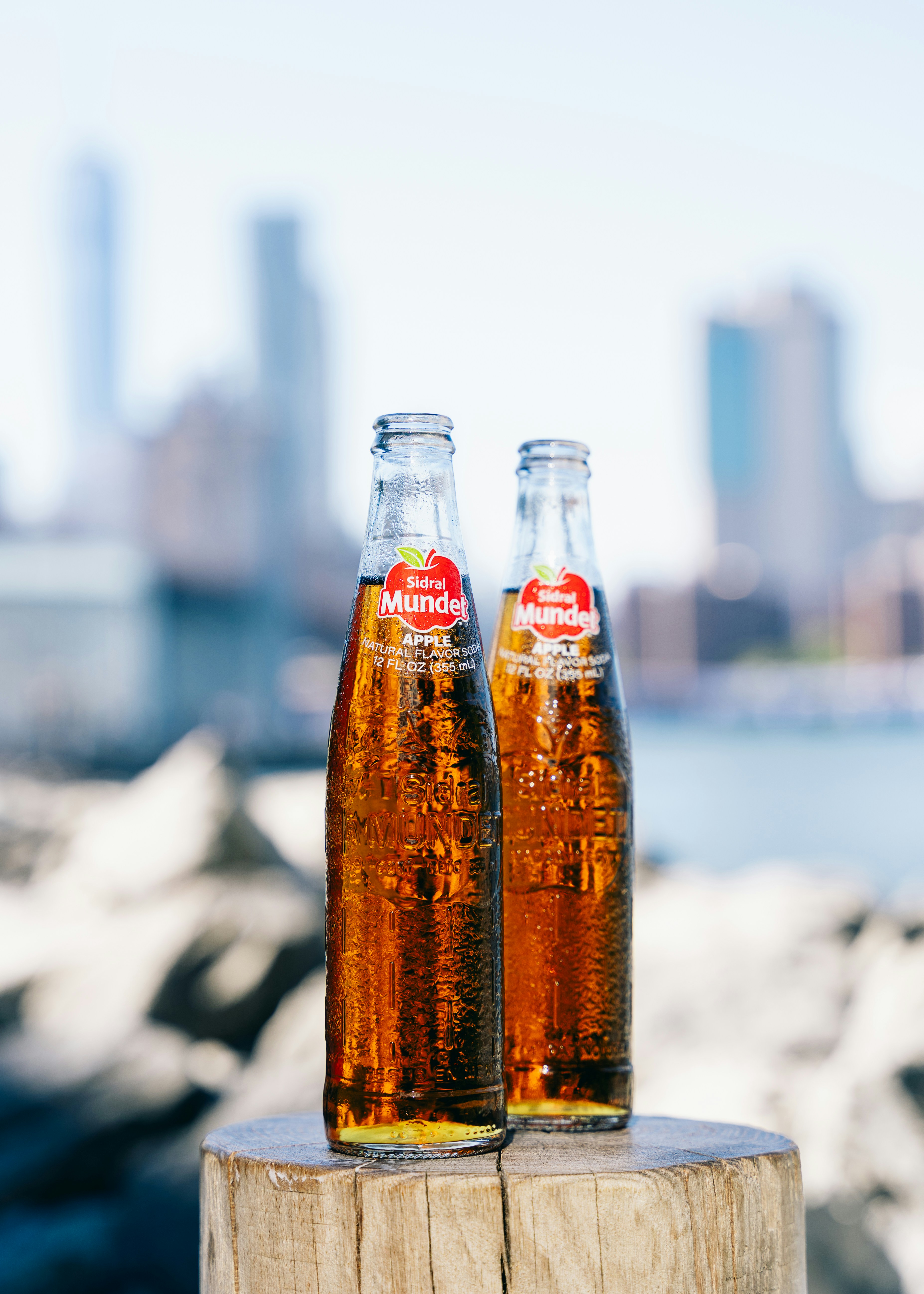 Two bottles of cider with a city skyline.