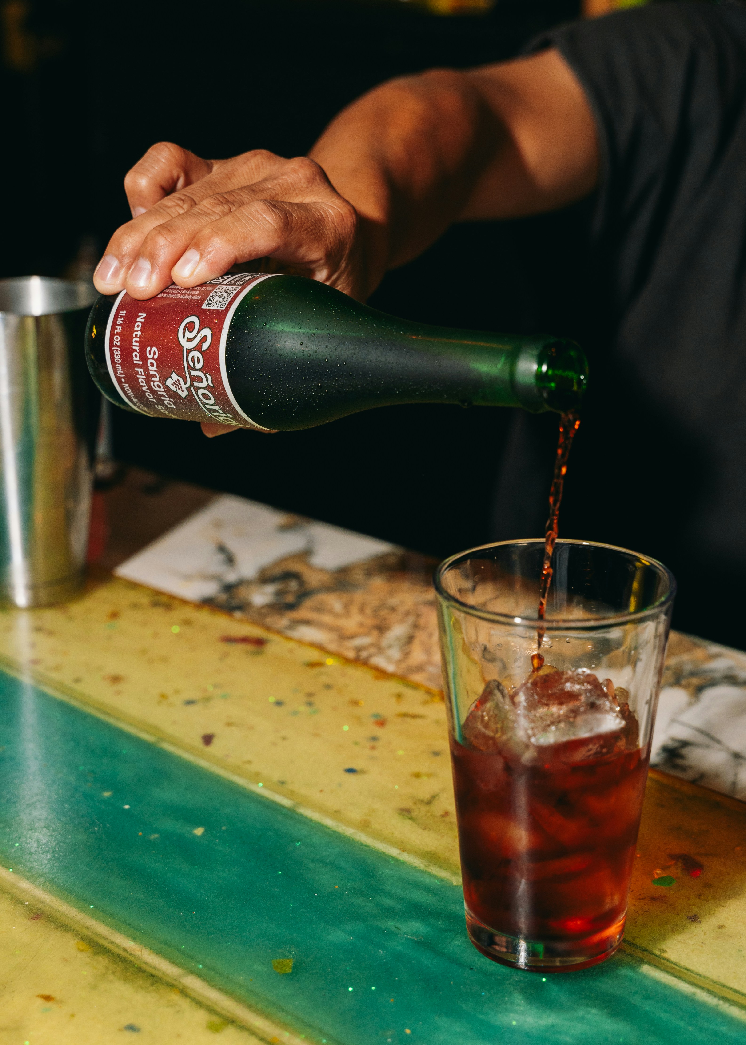 Someone is pouring a dark liquid into a glass.