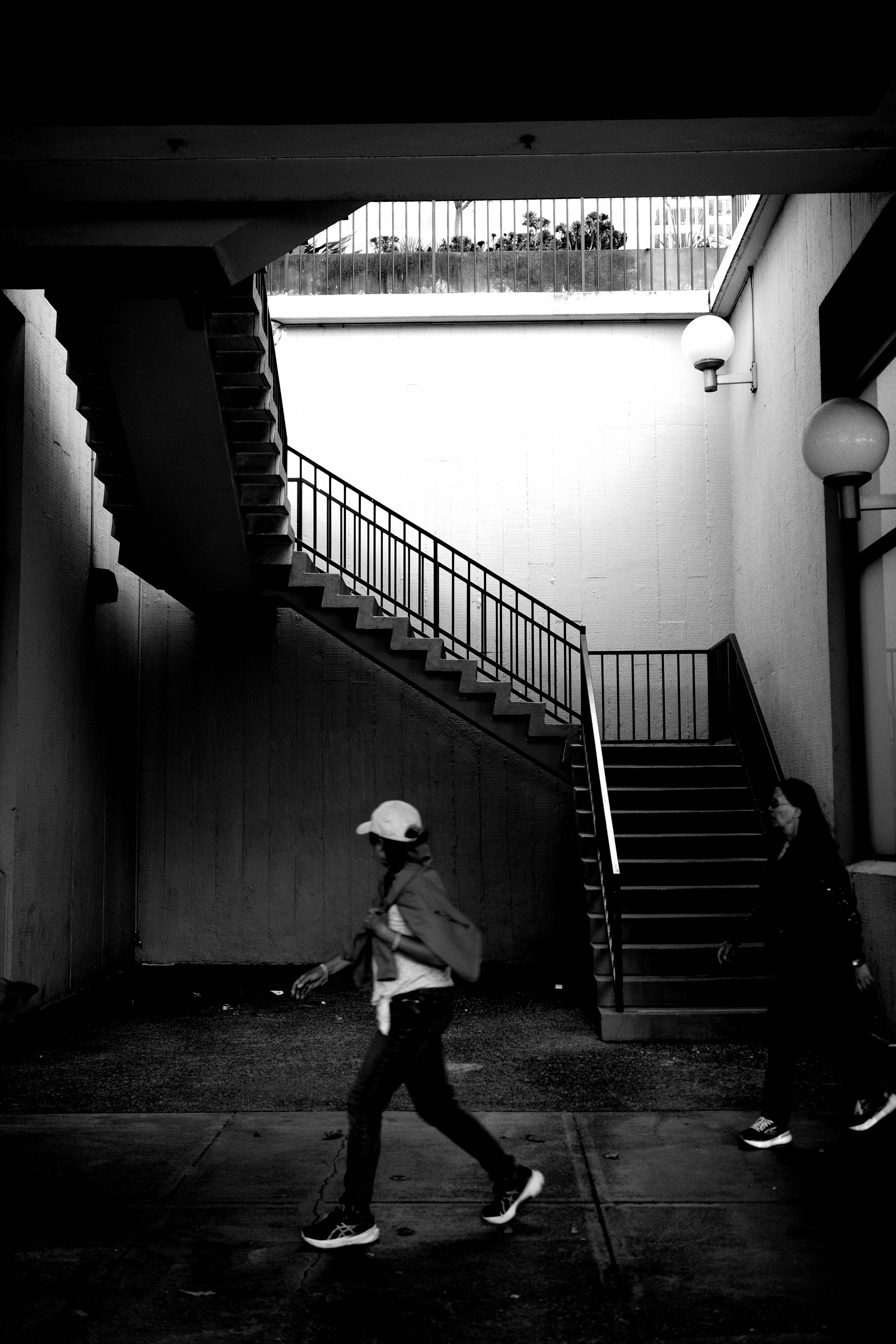 People walk past stairs in a black and white shot.