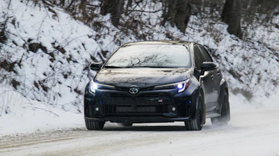 A black car drives through snowy conditions.
